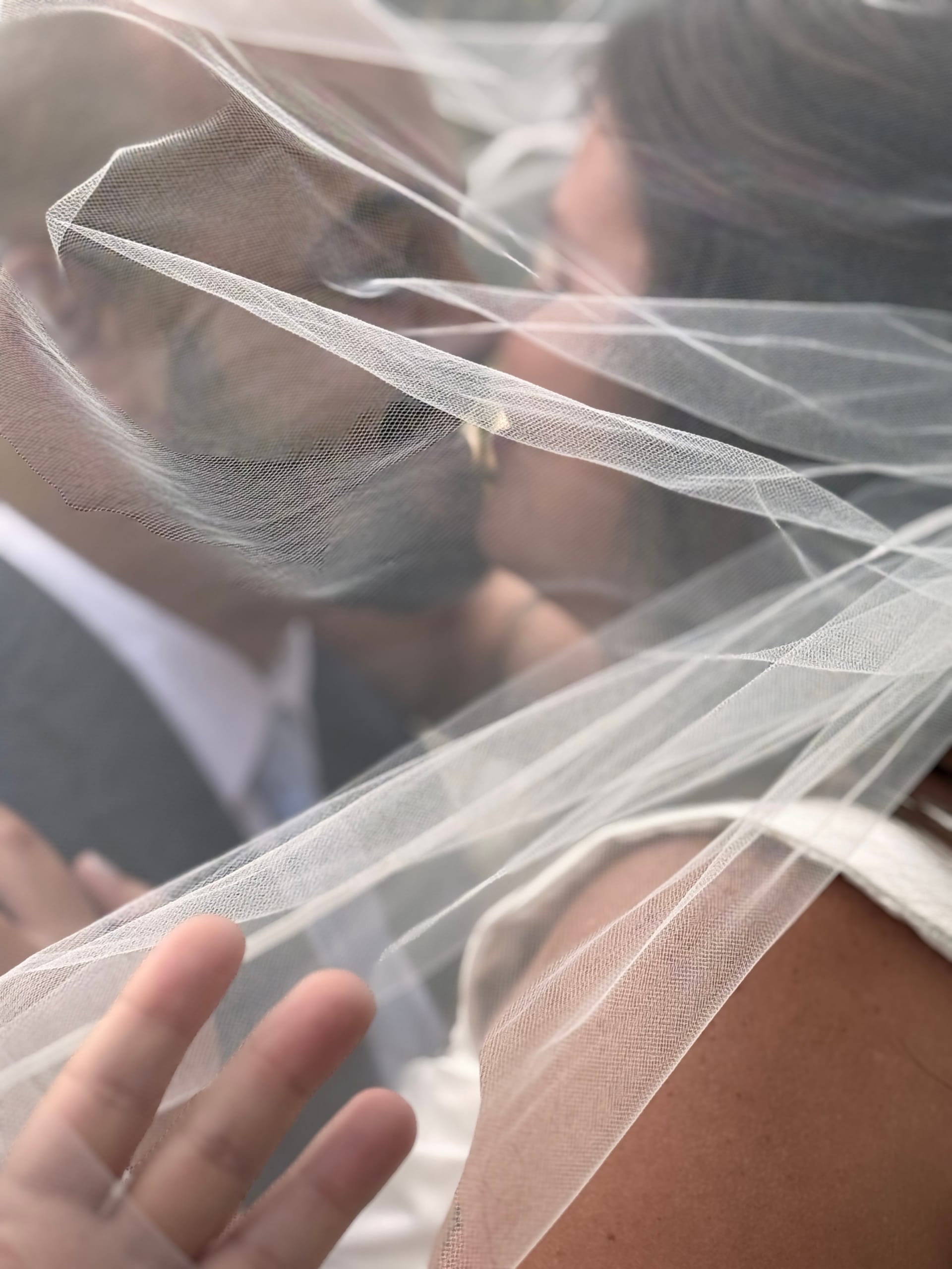 Bride and groom share a kiss beneath a flowing white veil at an outdoor wedding ceremony at Scarborough House.