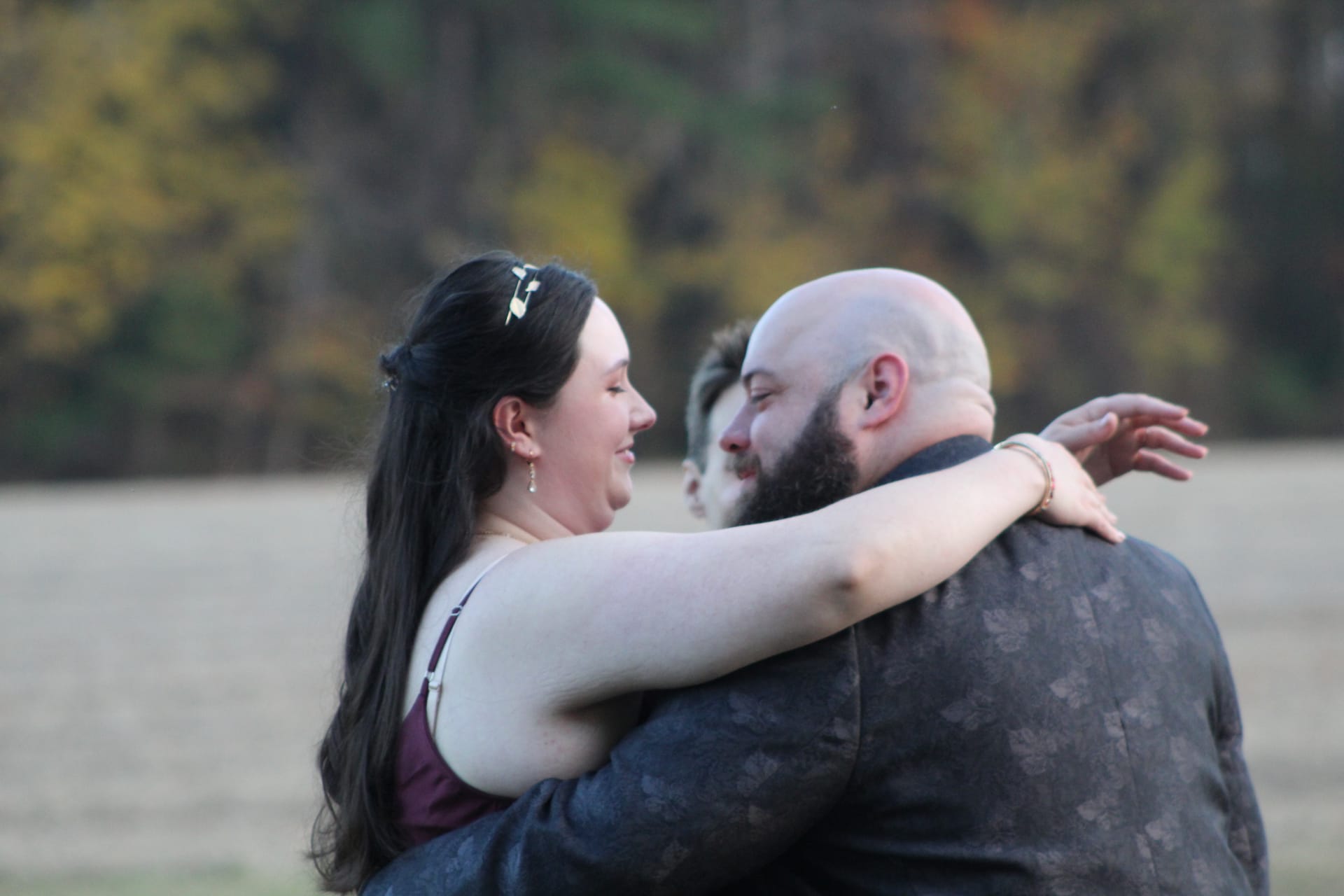 Bride and groom share a tender embrace and smile at each other during an outdoor moment on the farmland fields at Scarborough House, surrounded by soft autumn foliage.