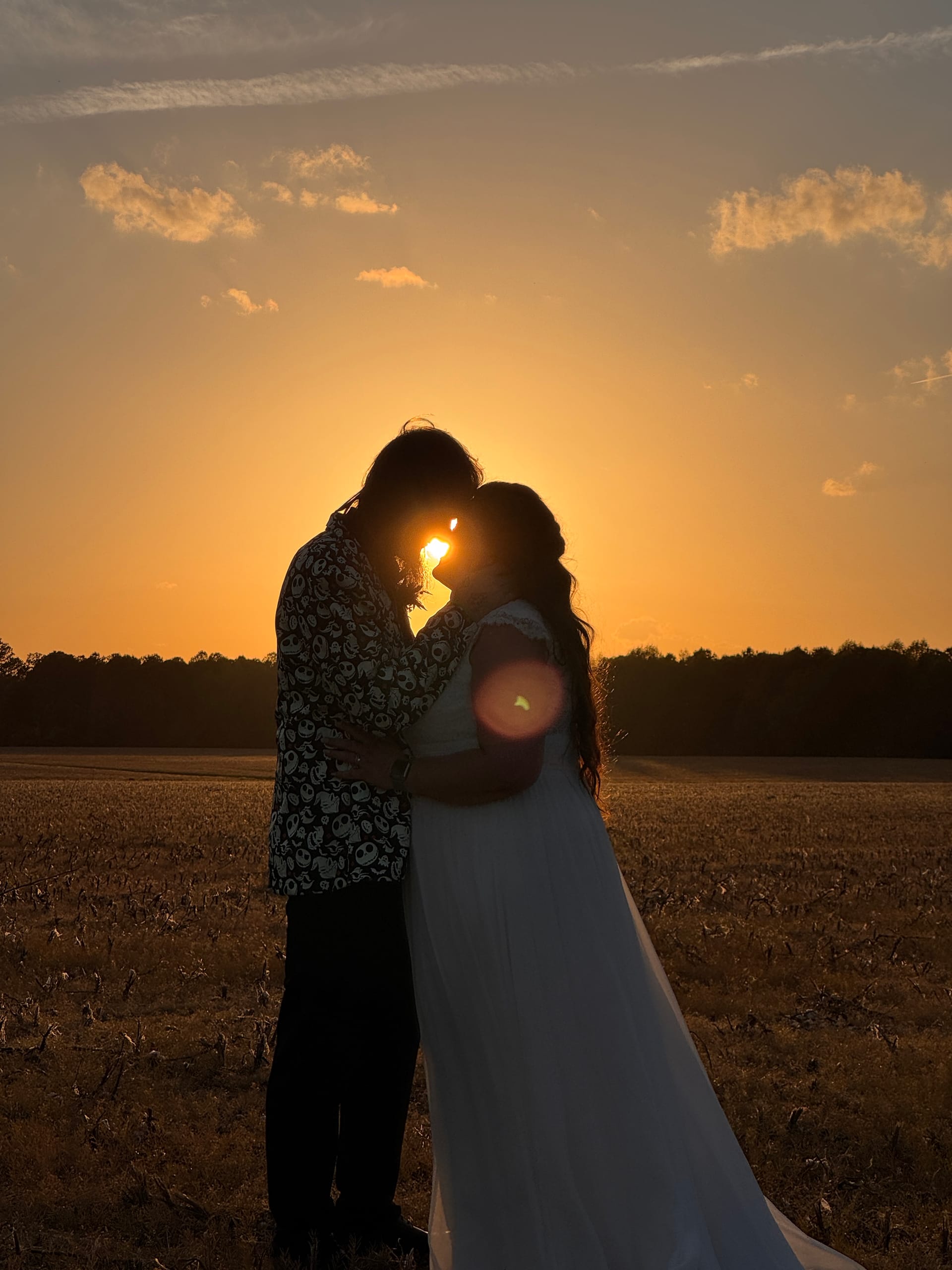Bride and groom share an intimate forehead-touch silhouetted against a glowing golden sunset over open farmland fields at Scarborough House.