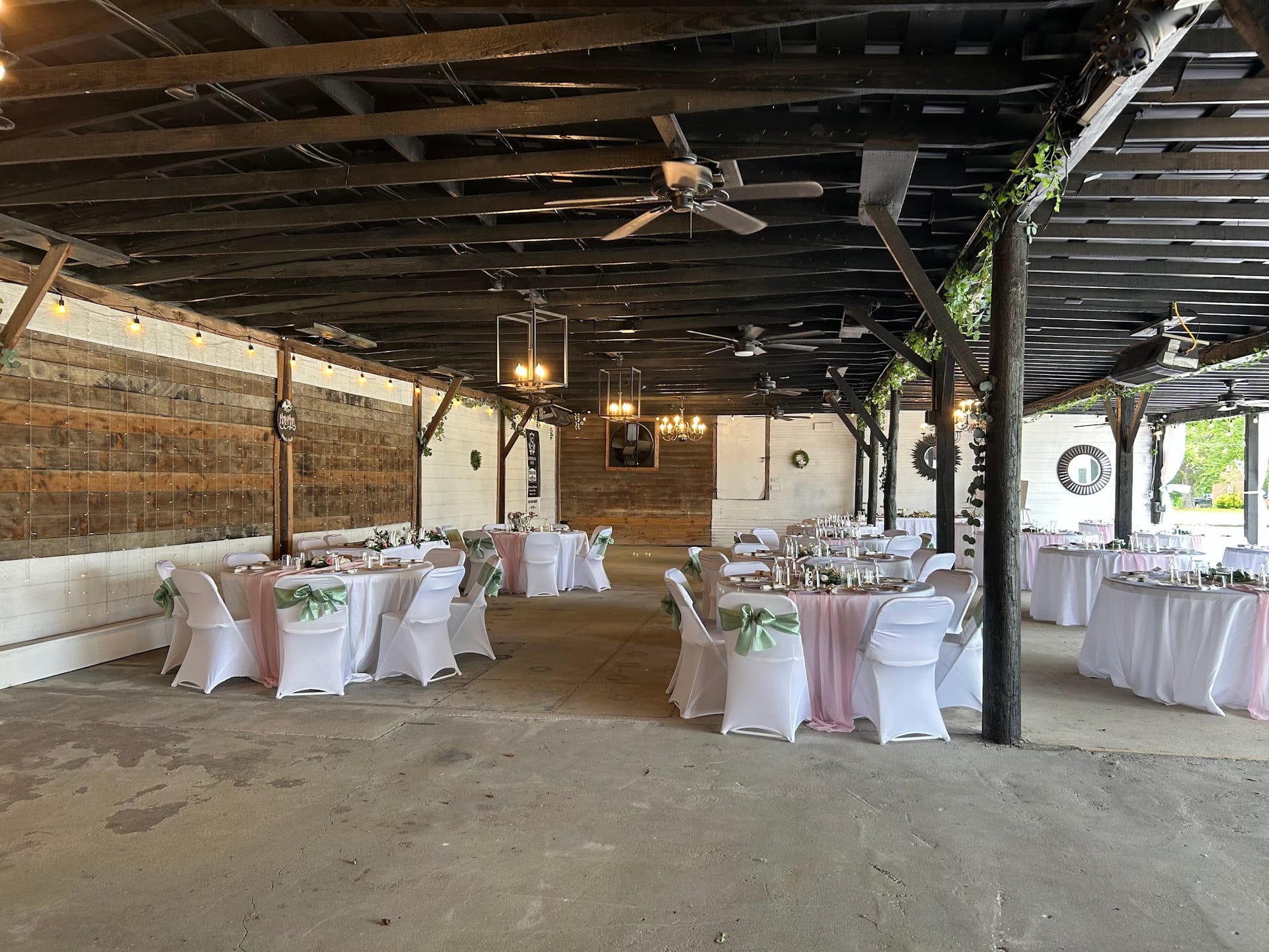 Elegantly set reception tables draped in pink linens with green sash chair covers beneath a rustic open-air pavilion at Scarborough House wedding venue.