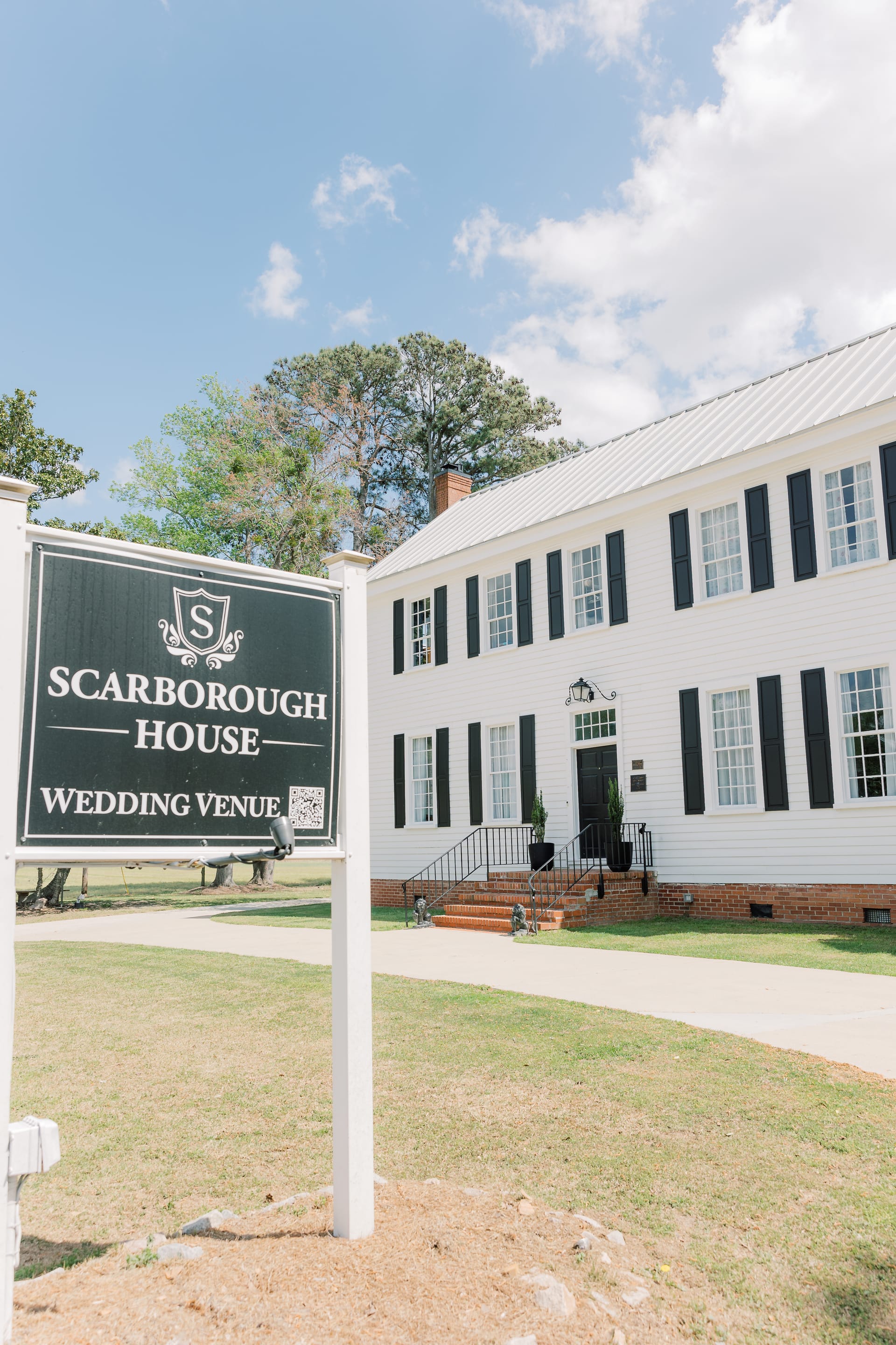 Scarborough House Wedding Venue sign in front of the historic white manor with black shutters.
