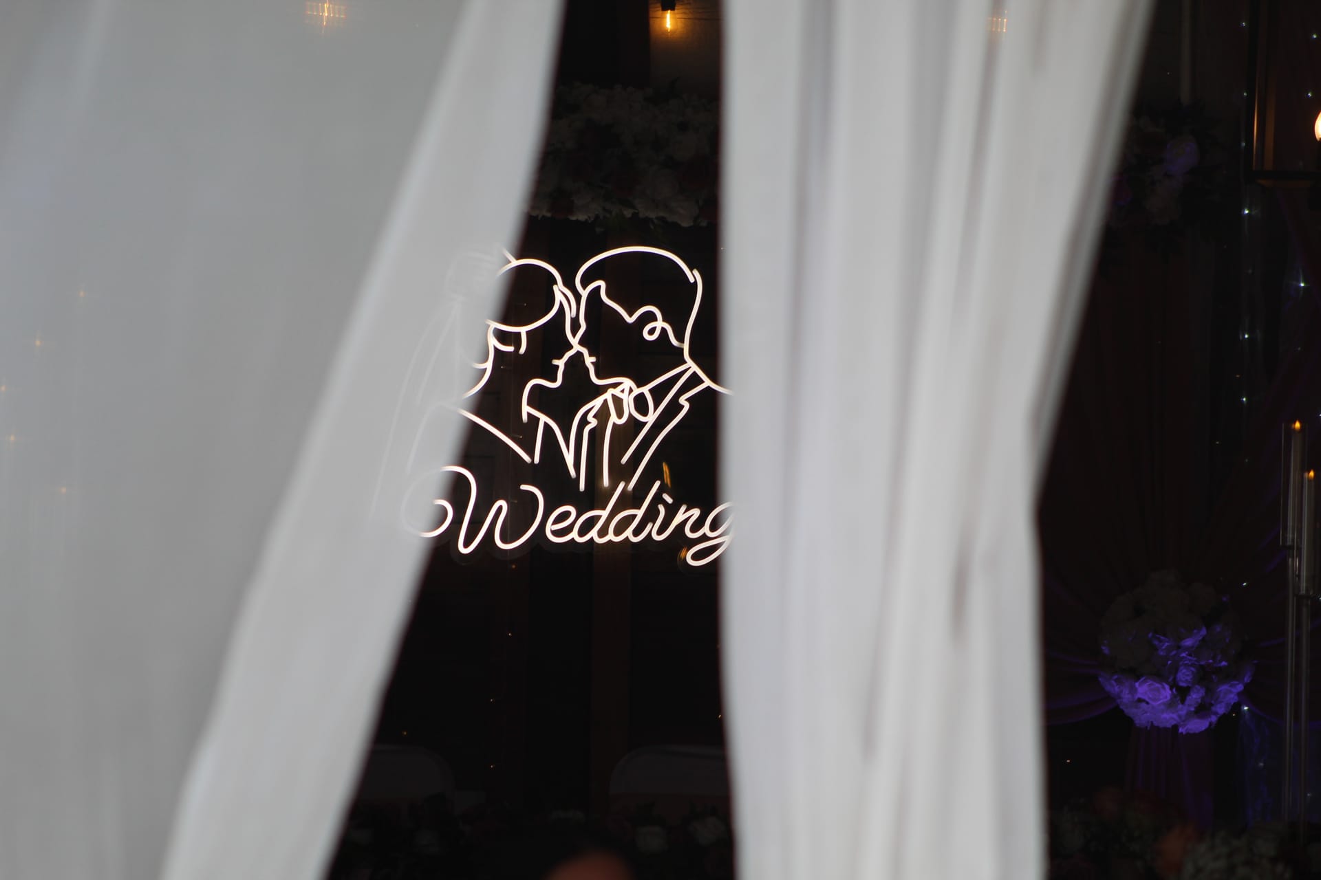Glowing white neon wedding sign featuring a couple silhouette framed by elegant white draping curtains inside the grand hall at Scarborough House.