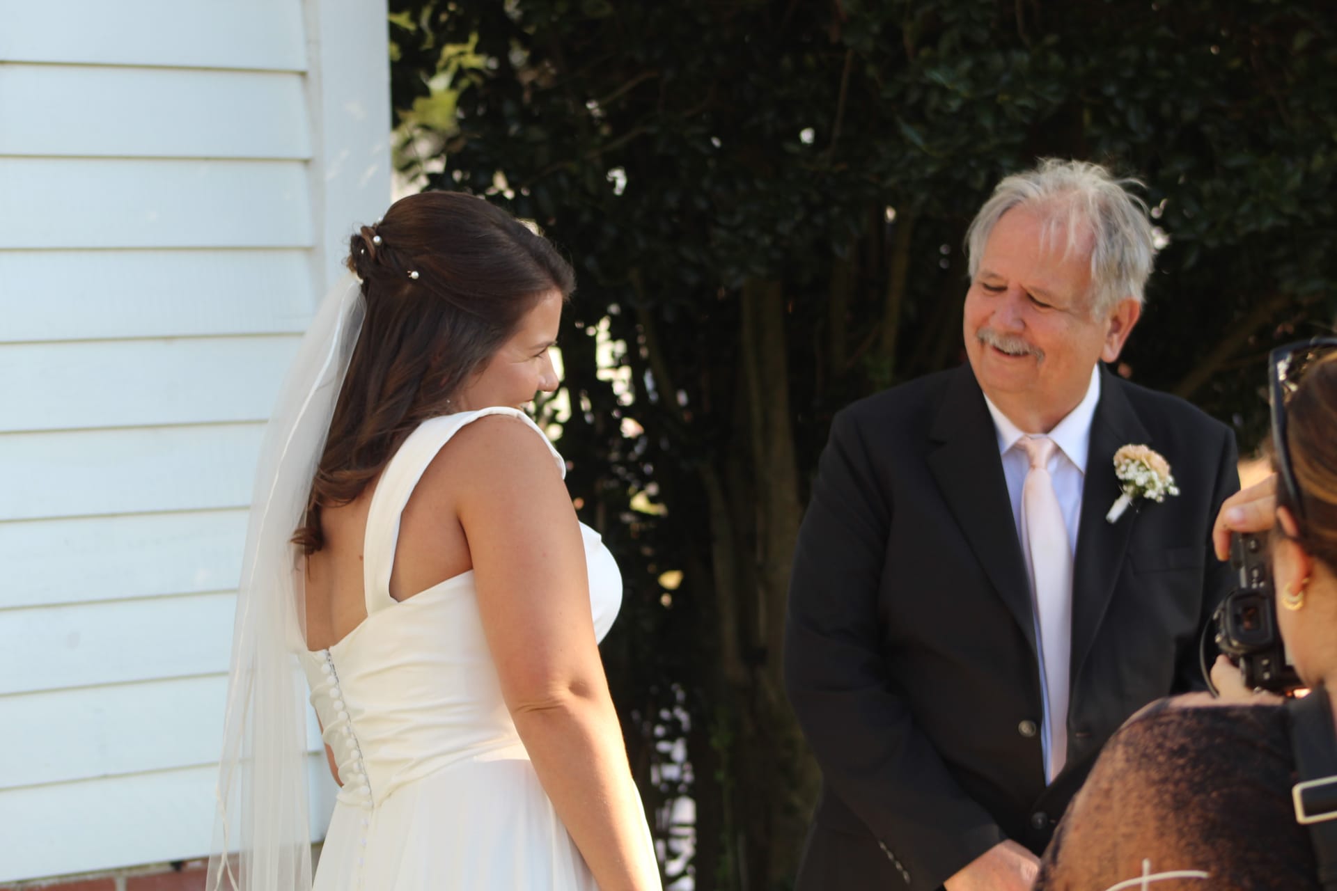 An older gentleman in a black suit sharing a warm moment with a bride outside a historic estate, representing the human relationships behind the CRM data.