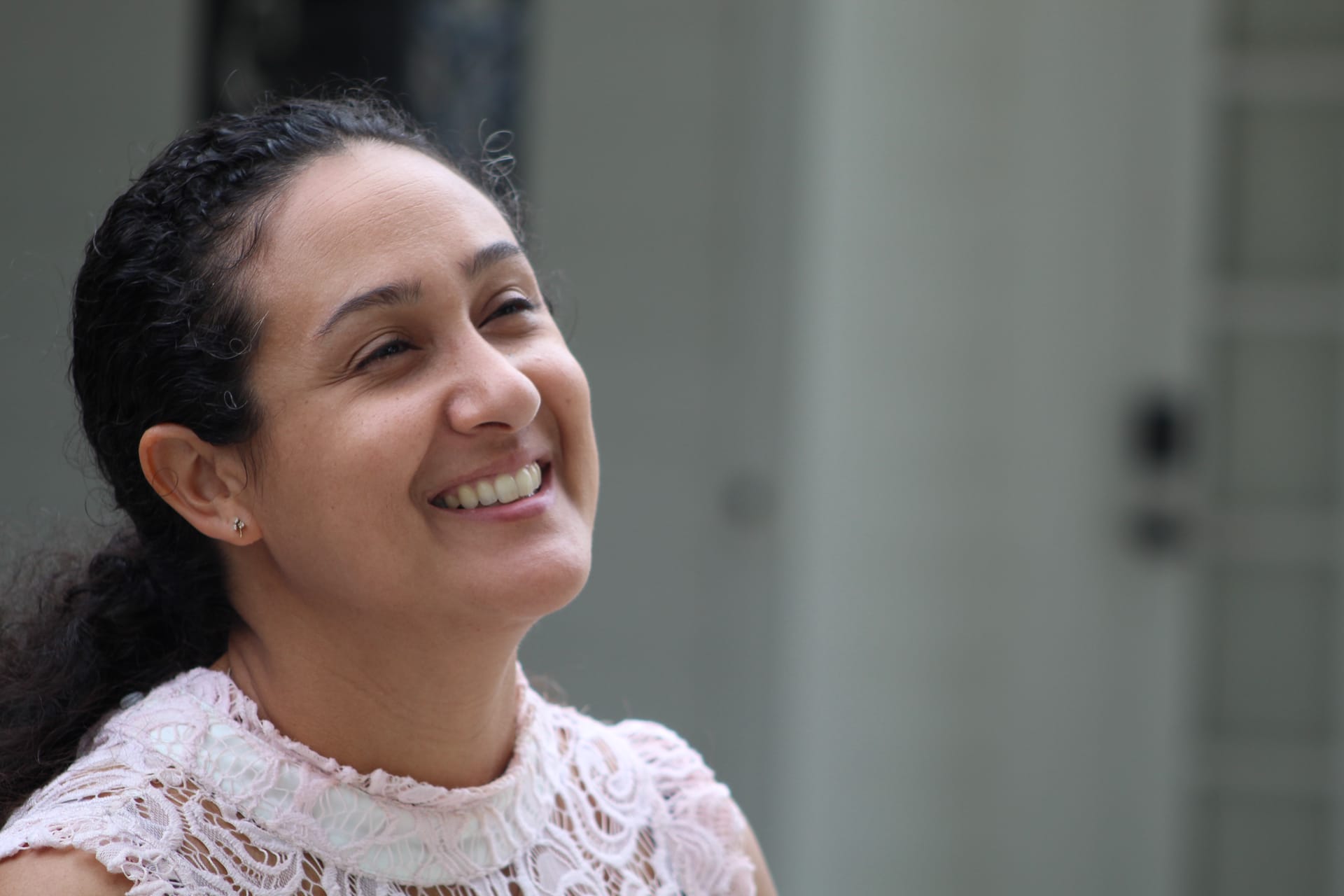 A smiling woman in a delicate lace top looks upward joyfully in the outdoor garden setting at Scarborough House estate.