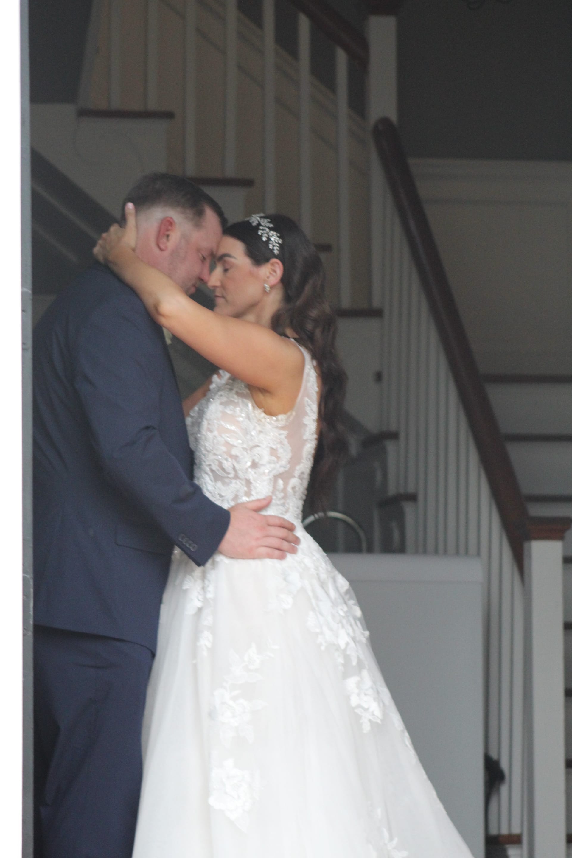 Bride and groom share a tender forehead-to-forehead embrace in the grand hall staircase of Scarborough House historic estate wedding venue.