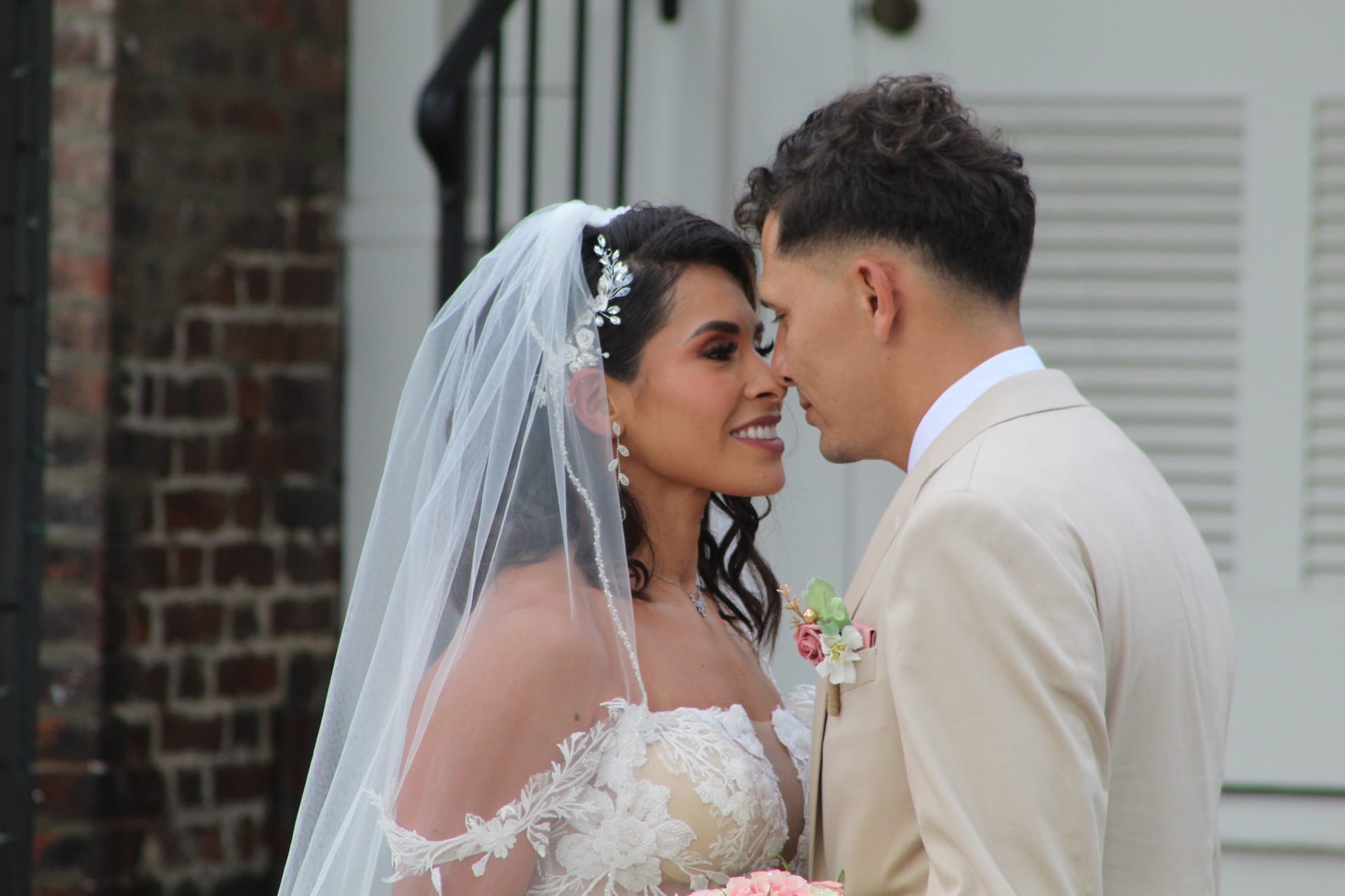 Bride in lace gown and veil smiling as she and groom touch foreheads outside the historic 1821 Scarborough House manor.