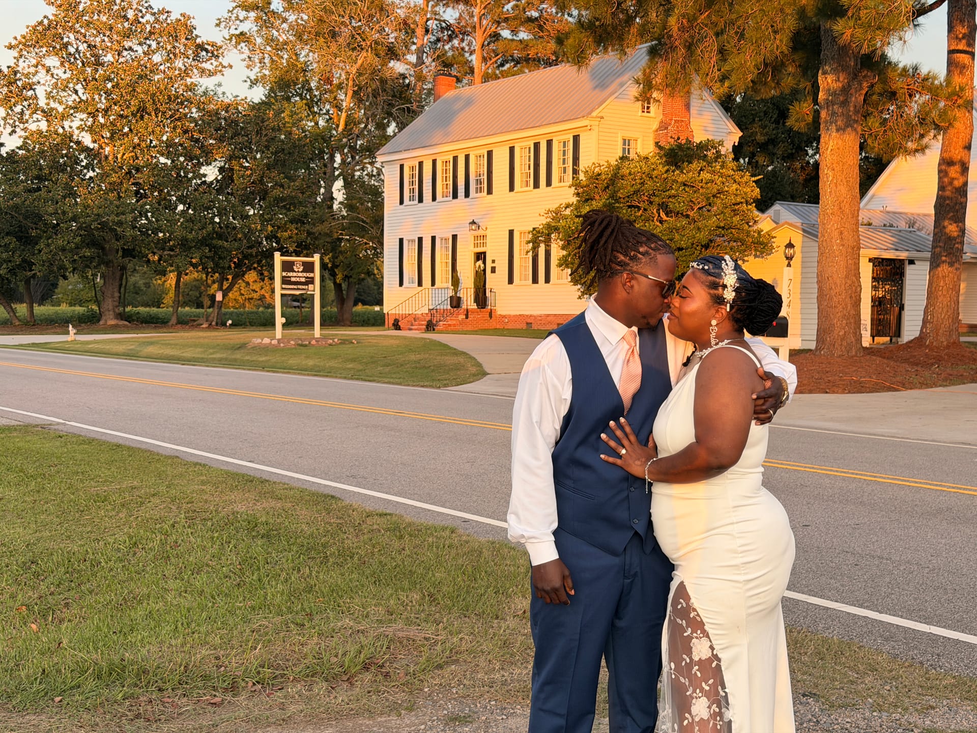 Bride and groom sharing a kiss at golden hour on the road in front of the historic 1821 Scarborough House manor estate.