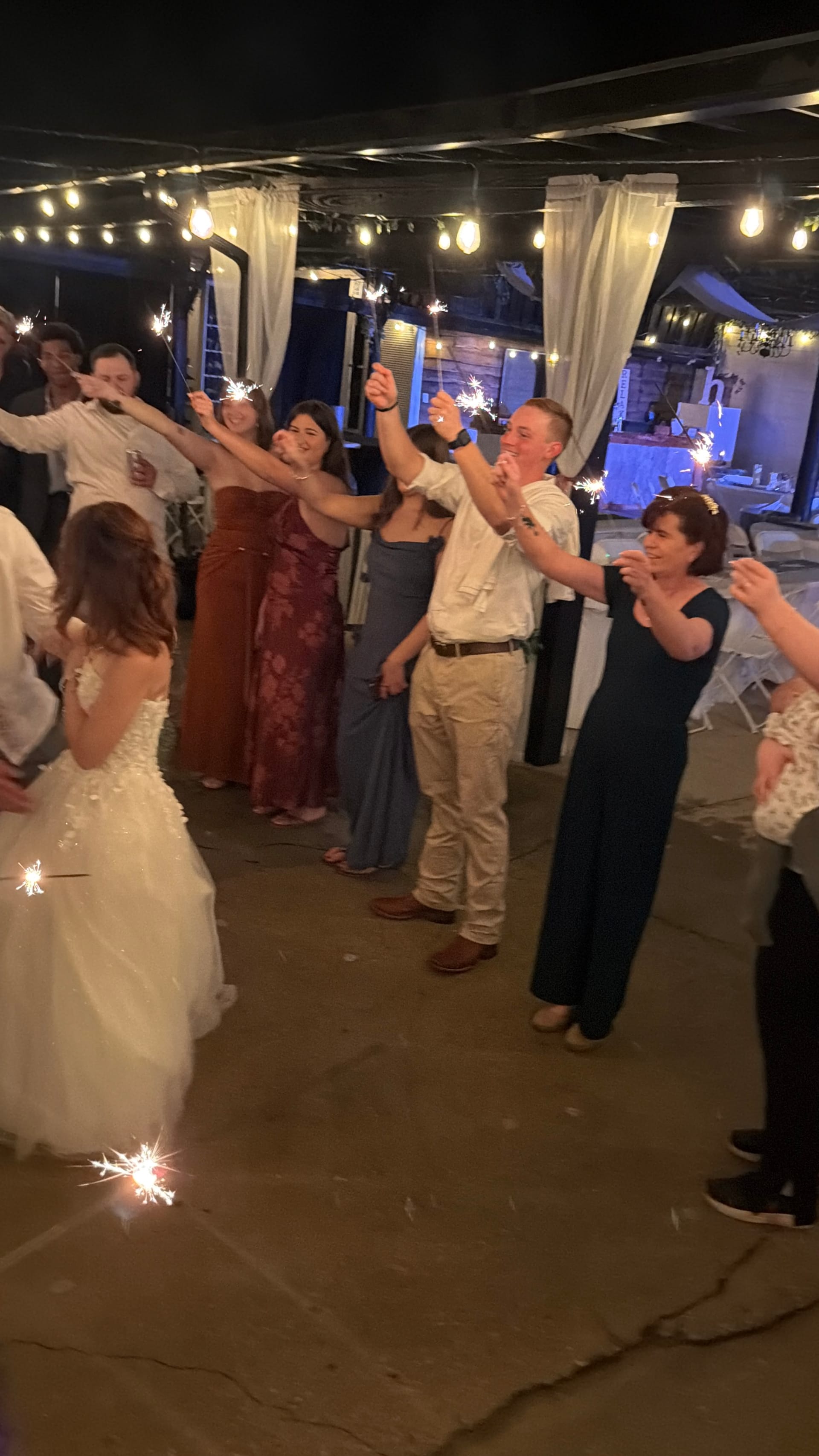 Wedding guests holding sparklers aloft to celebrate the bride during a festive nighttime send-off at Scarborough House estate venue.