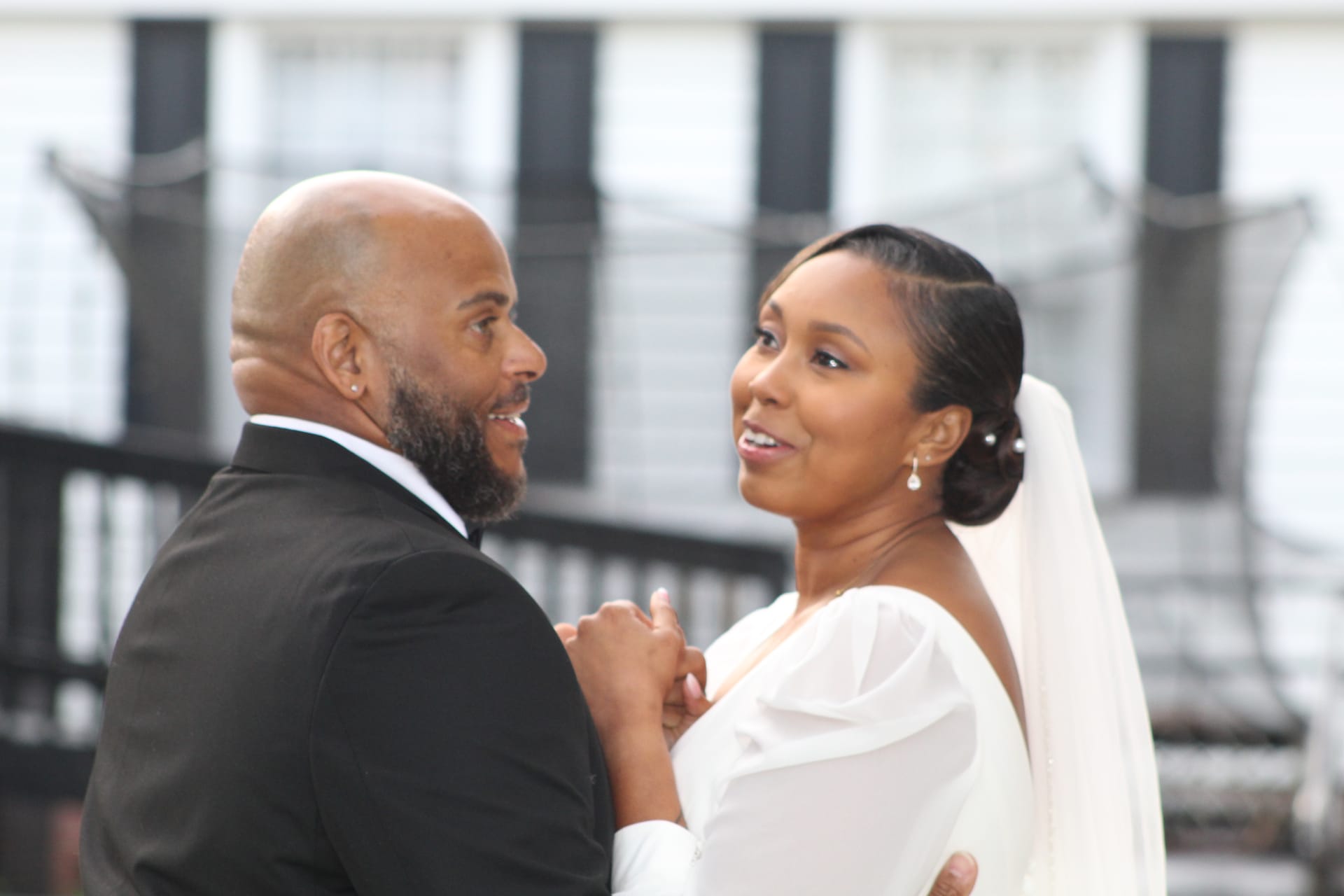 Bride in a white off-shoulder gown and veil smiles warmly at her groom in a black suit as they share a dance at Scarborough House historic estate wedding venue.