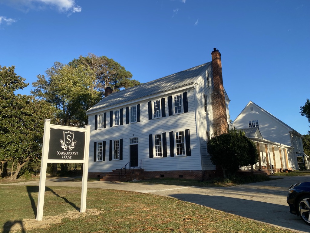 Front of the historic white Scarborough House with black shutters and the estate sign