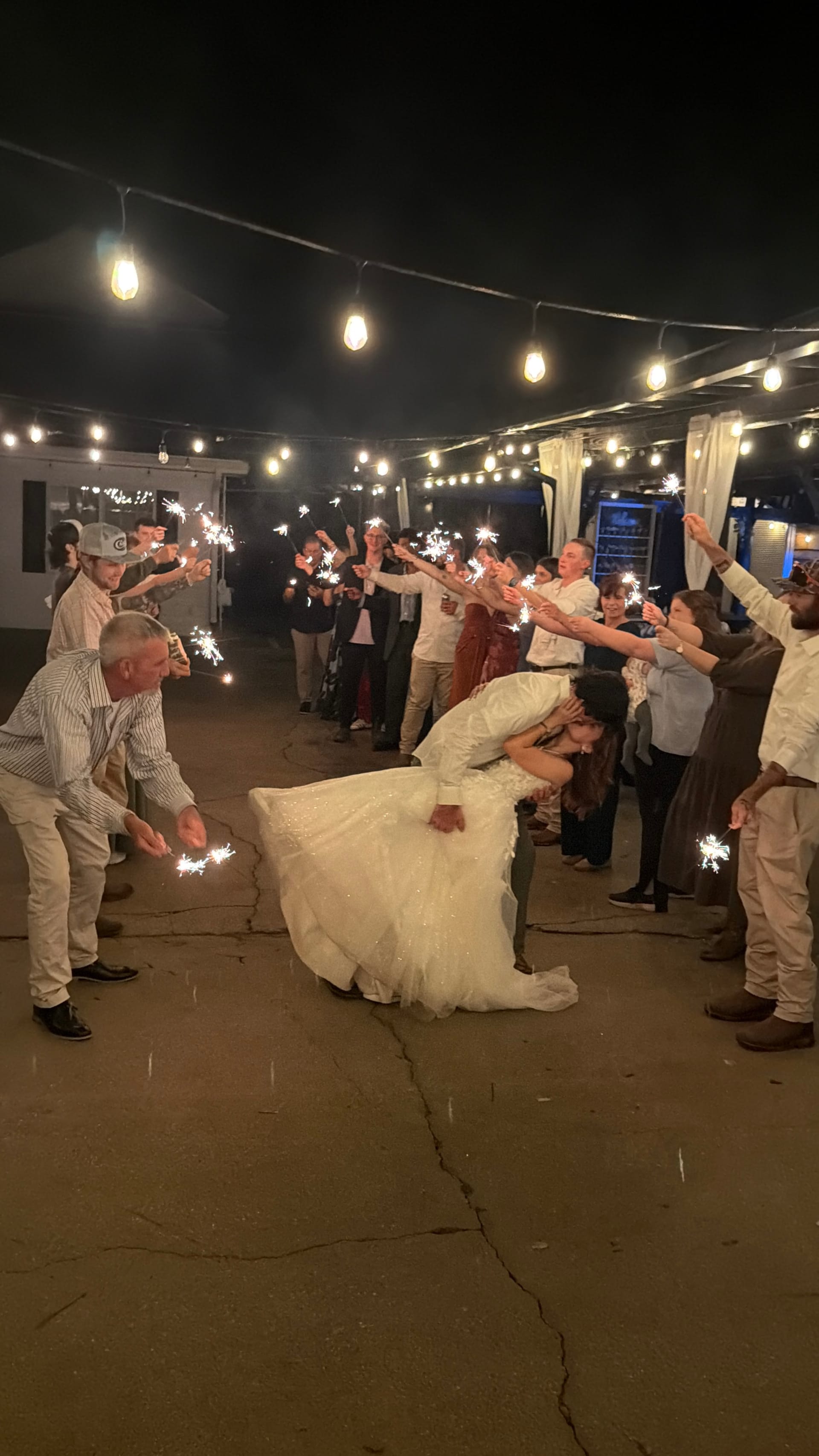 Bride and groom share a dramatic dip kiss during their sparkler exit as guests line the path under warm string lights at Scarborough House.