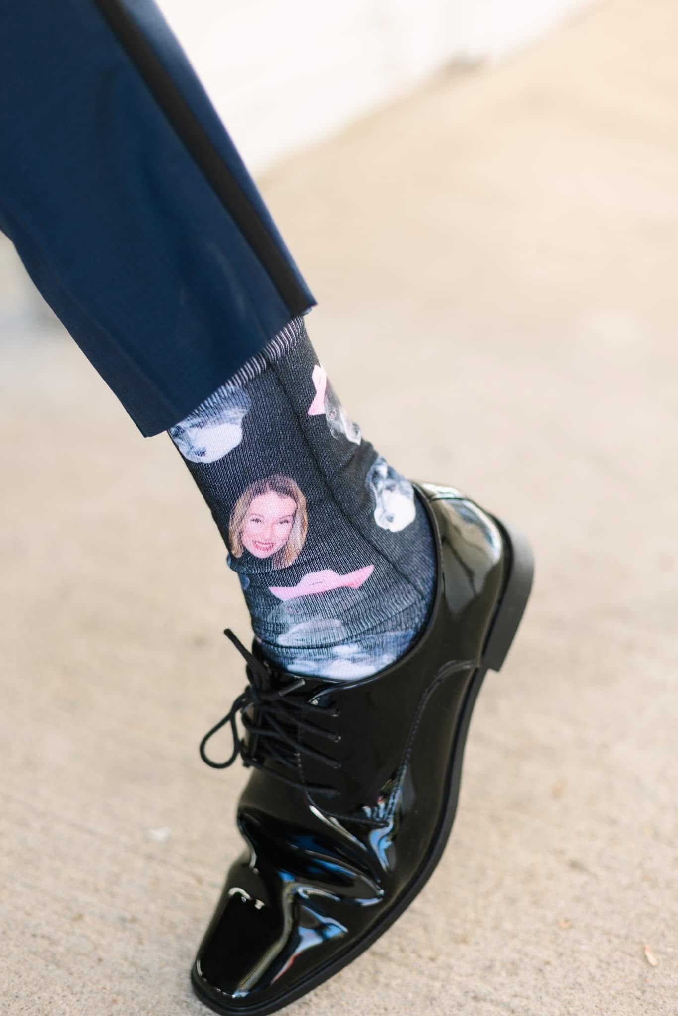 Close-up of a groom's custom photo socks printed with his bride's face worn with polished black patent leather dress shoes and navy suit trousers.
