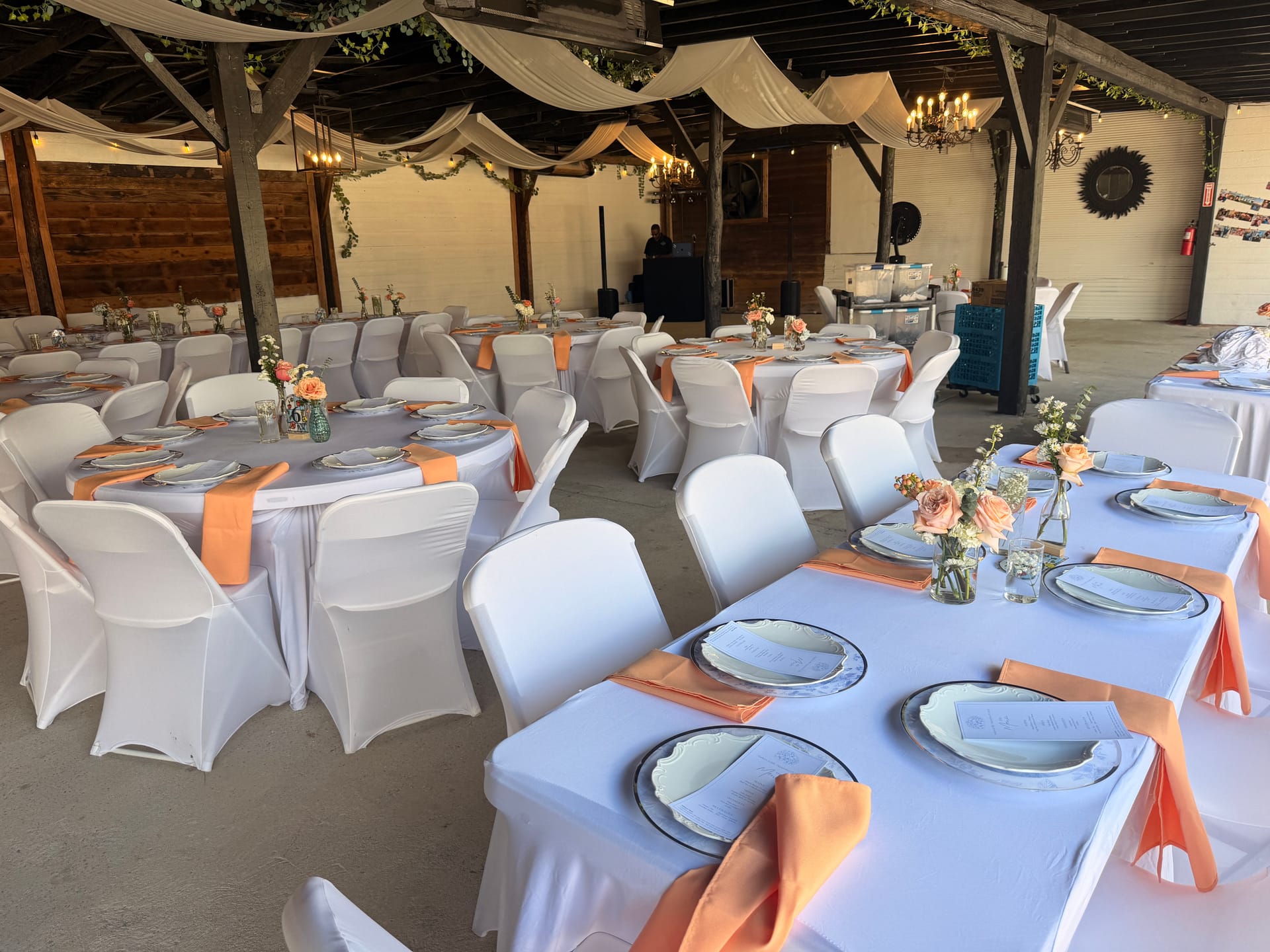 Elegantly set reception tables with white linens, peach napkins, and rose centerpieces under a draped rustic pavilion at Scarborough House.