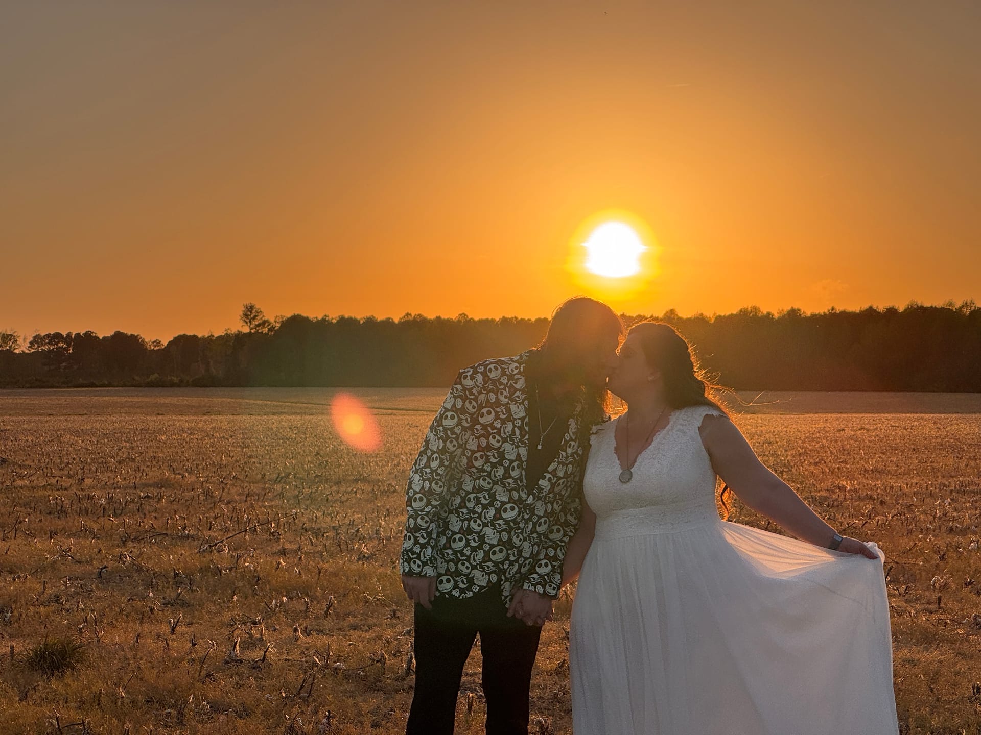 Bride and groom share a sunset kiss in an open farmland field bathed in warm golden light at Scarborough House historic estate.