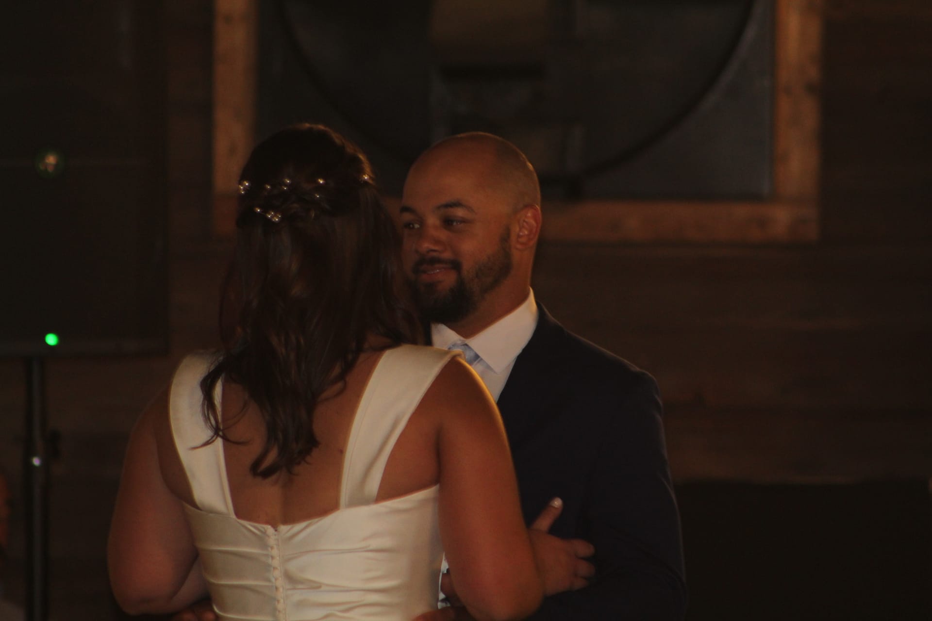Bride and groom share their first dance in the warmly lit grand hall at Scarborough House, the groom smiling tenderly as he holds his bride close.