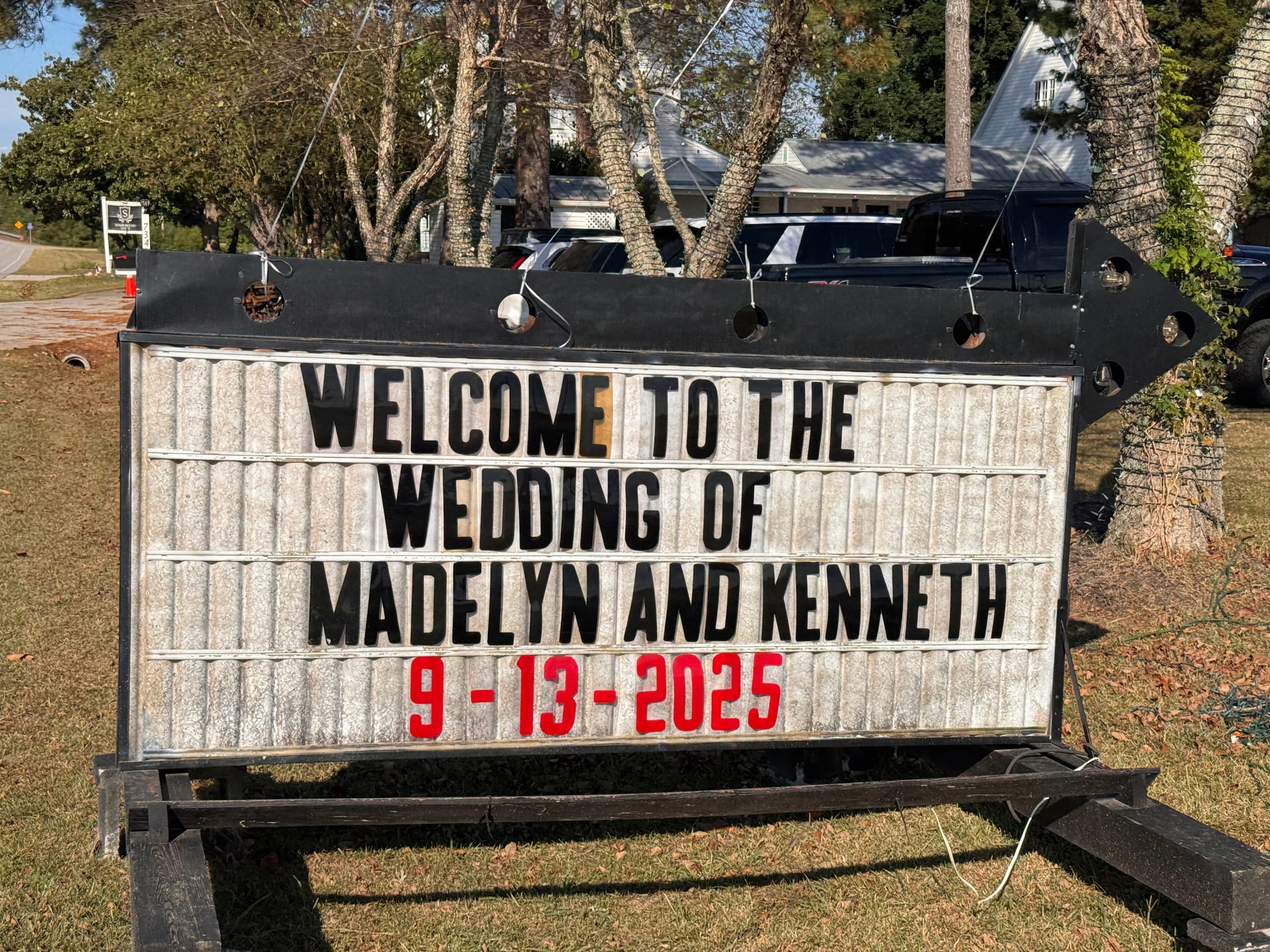 Outdoor marquee arrow sign reading Welcome to the Wedding of Madelyn and Kenneth 9-13-2025 displayed on the grounds of a historic estate wedding venue.