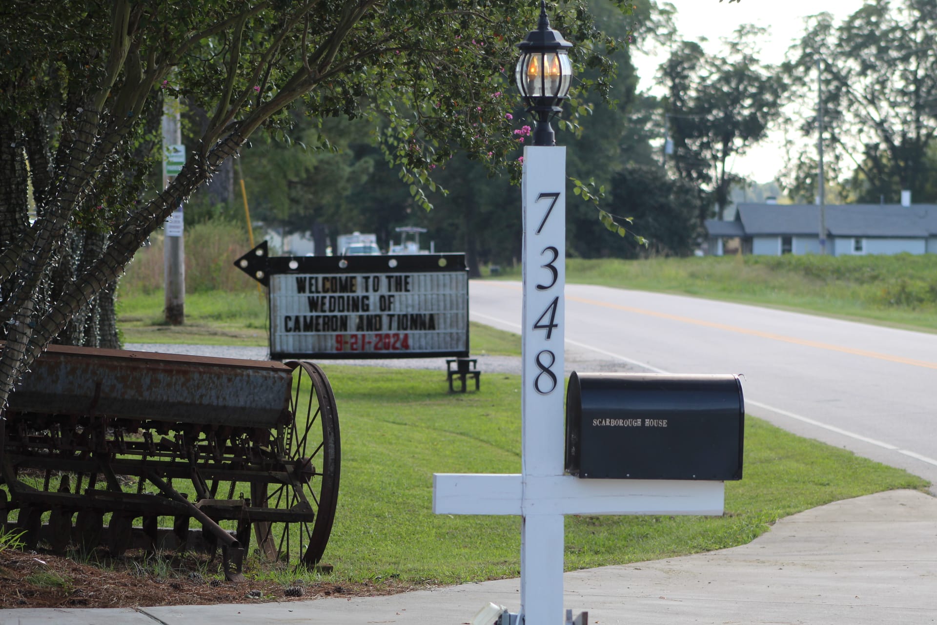 Welcome wedding marquee sign for Cameron and Tionna dated September 21 2024 displayed at the entrance of Scarborough House historic wedding venue alongside vintage farm equipment and a white address post.