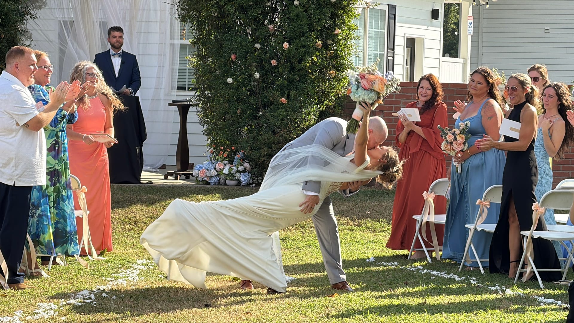 Groom dips bride for a dramatic kiss during their wedding recessional on the ceremony lawn at Scarborough House as guests cheer and applaud.