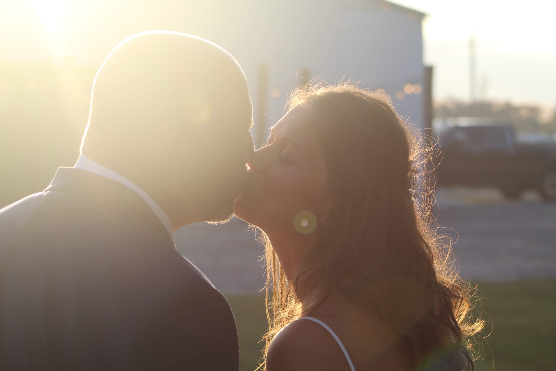 Couple sharing a romantic kiss bathed in warm golden sunset light with a soft lens flare at Scarborough House wedding venue.