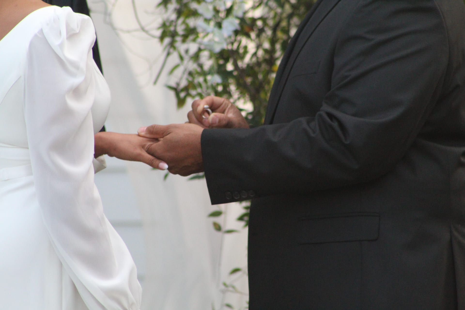 Groom placing a wedding ring on the bride's finger during the outdoor ceremony at Scarborough House historic estate venue.
