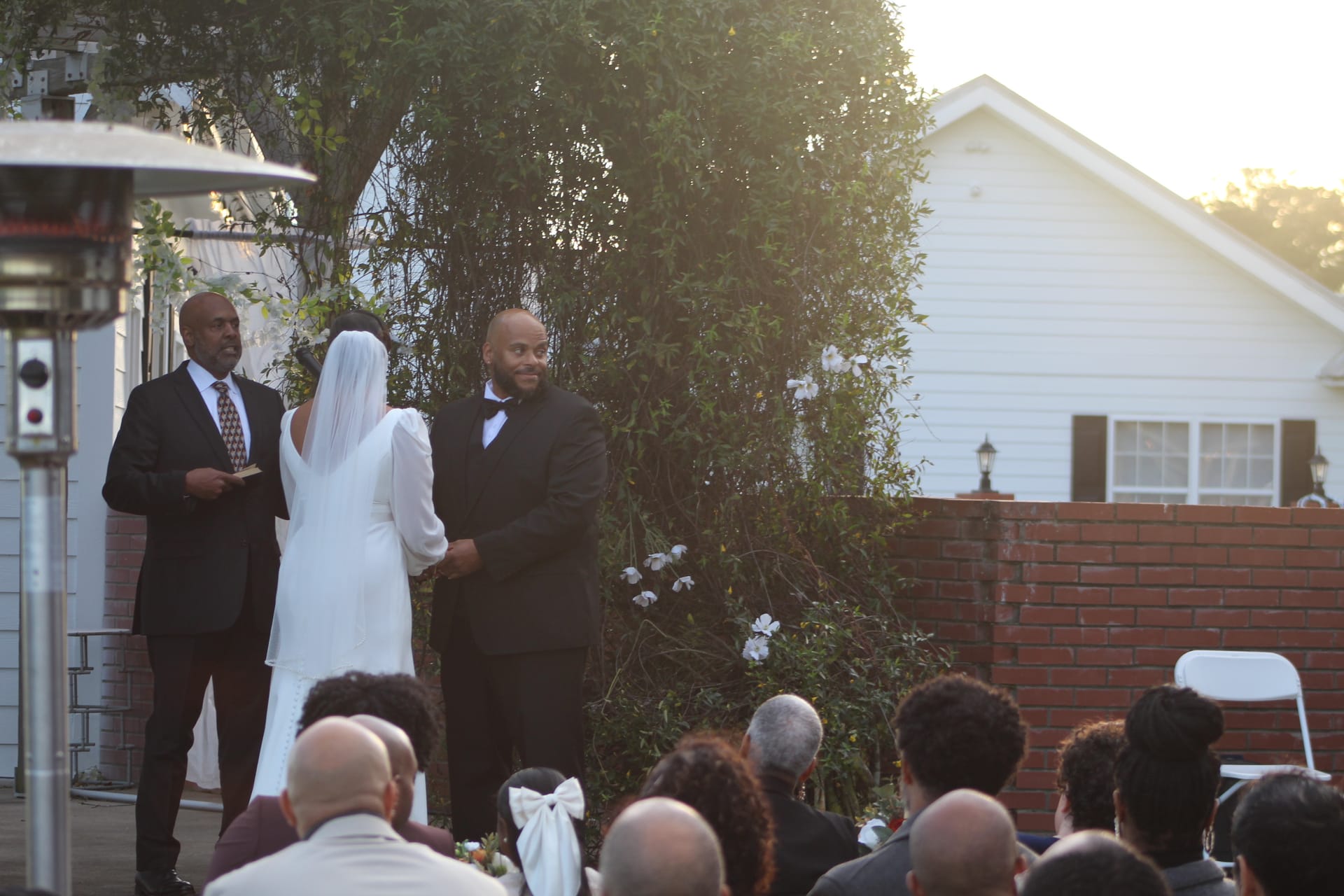 Groom smiles warmly at his bride during an intimate outdoor wedding ceremony on the garden lawn at Scarborough House historic estate.