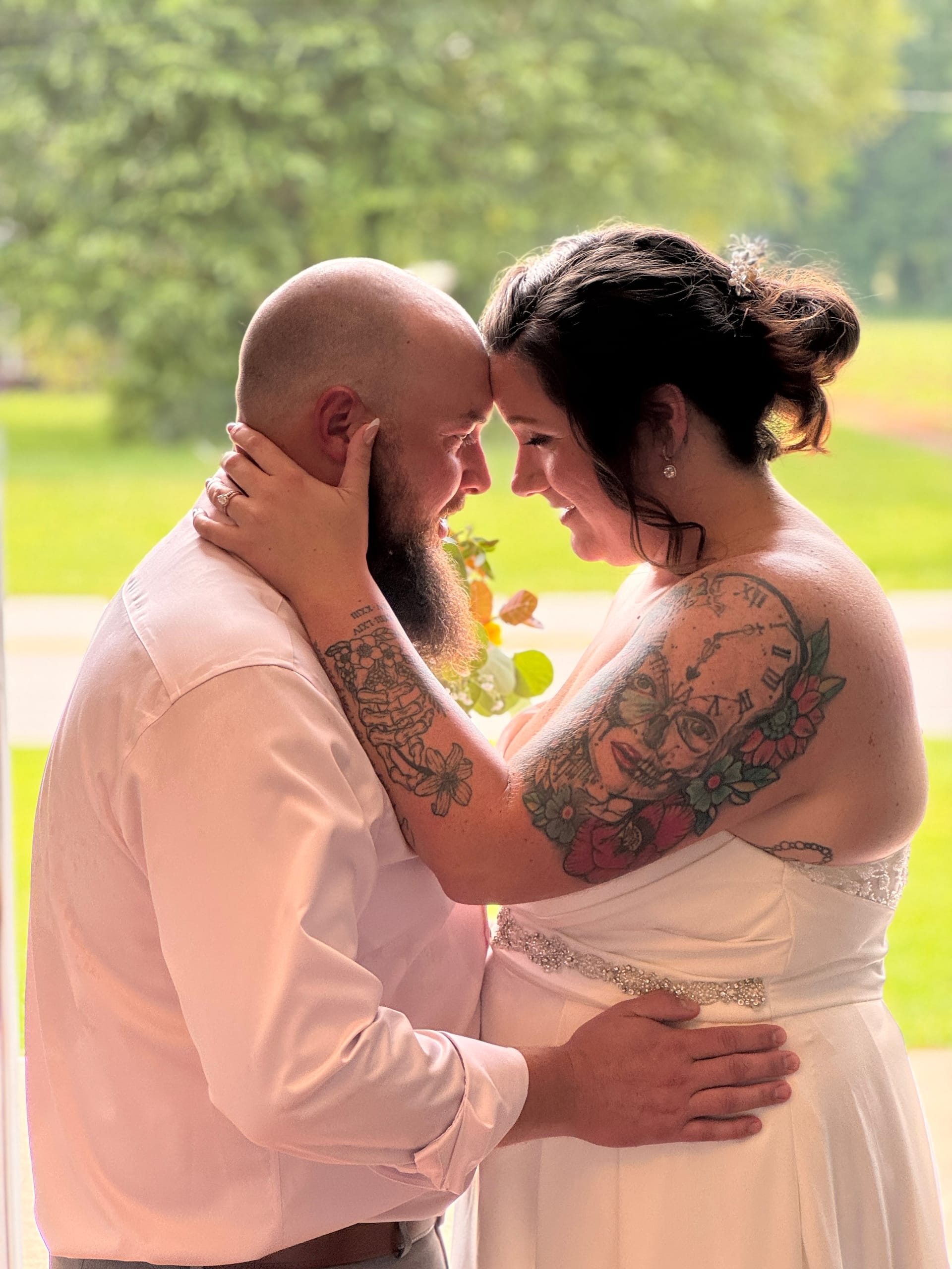 Bride and groom touch foreheads and smile at each other in a tender romantic portrait bathed in soft natural window light at Scarborough House wedding venue.