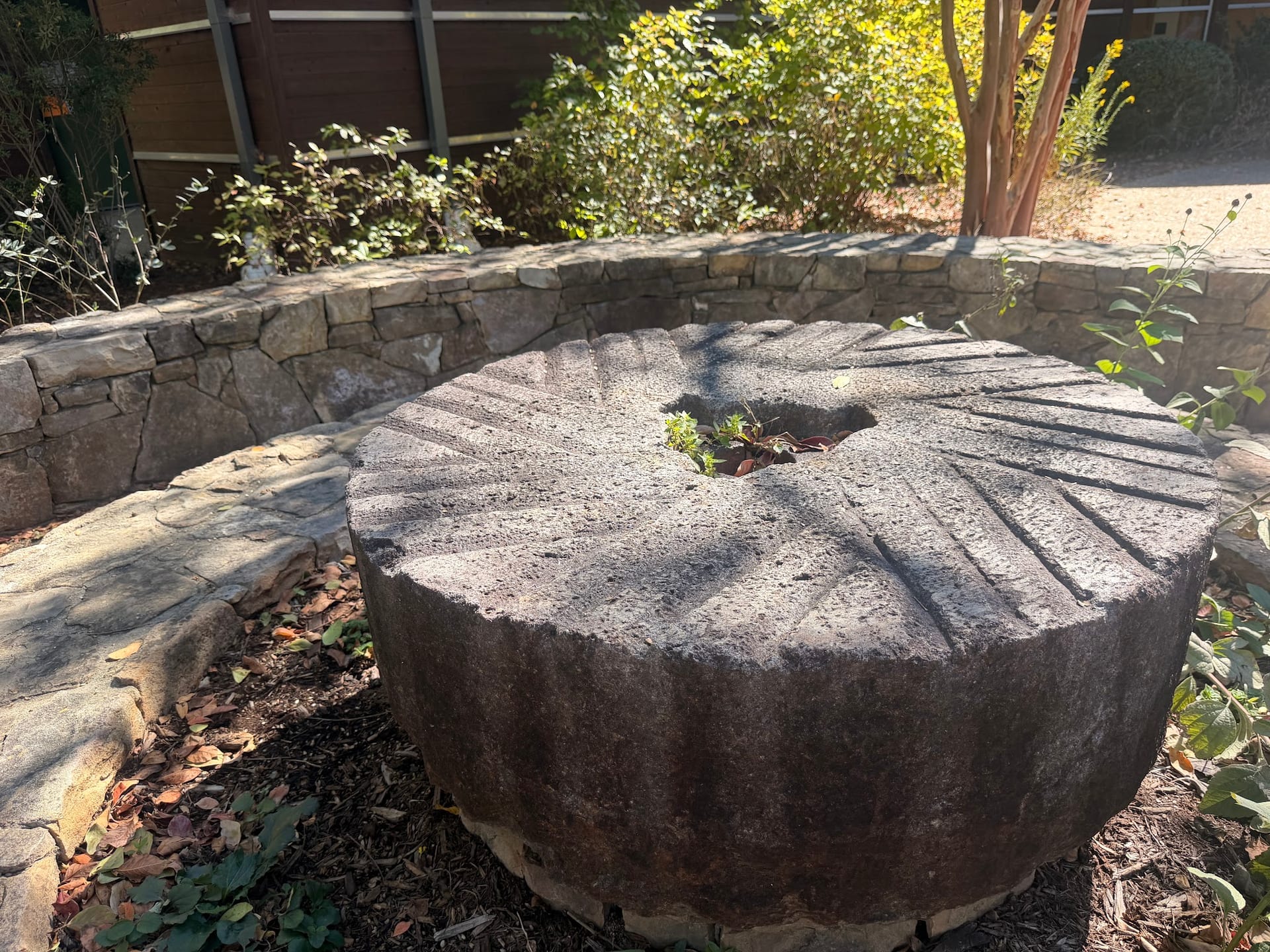 Historic millstone beside a planted stone border at Yates Mill