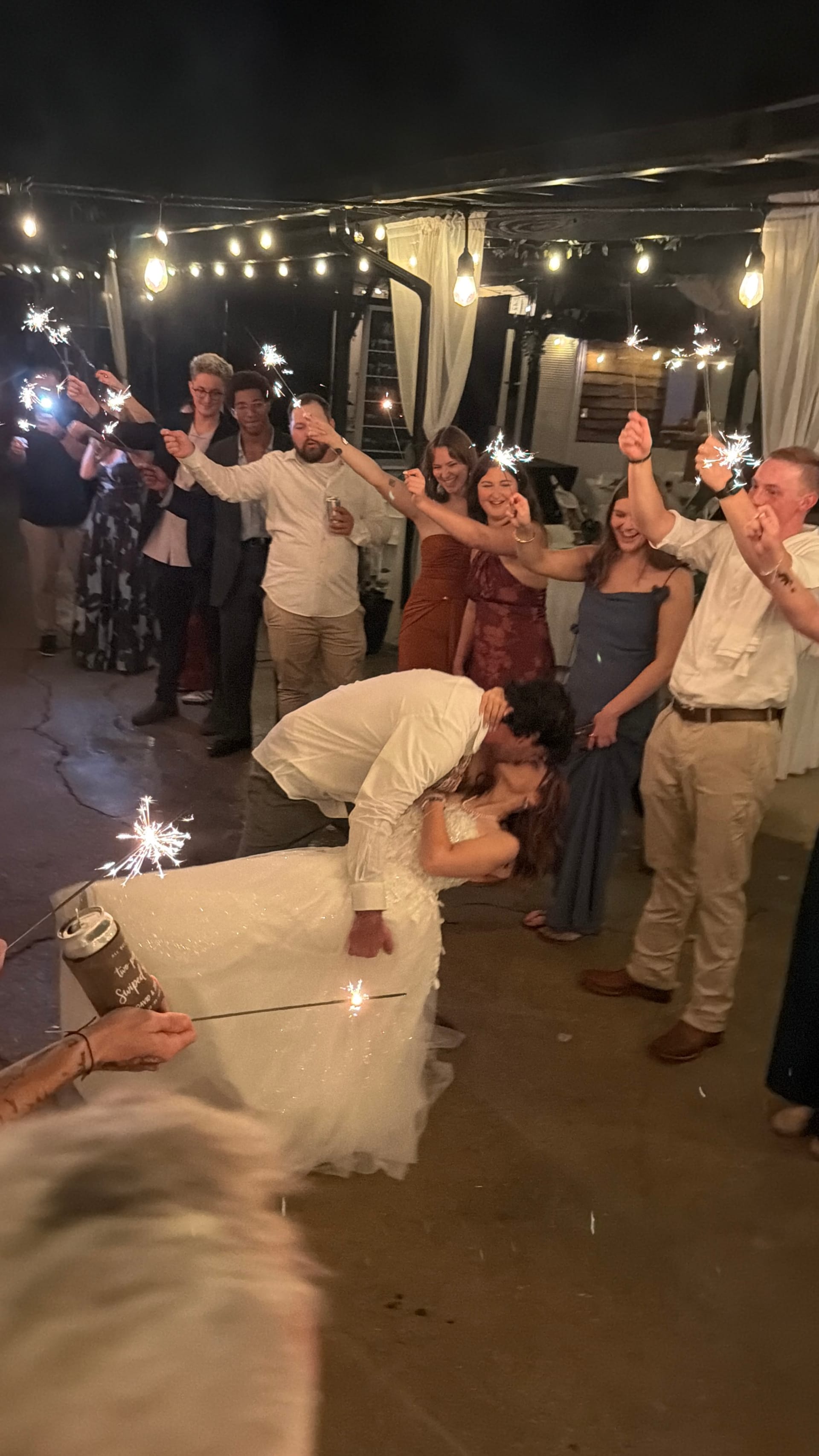 Bride and groom share a dramatic dip kiss during their sparkler send-off as cheering guests line the path under warm string lights at Scarborough House.