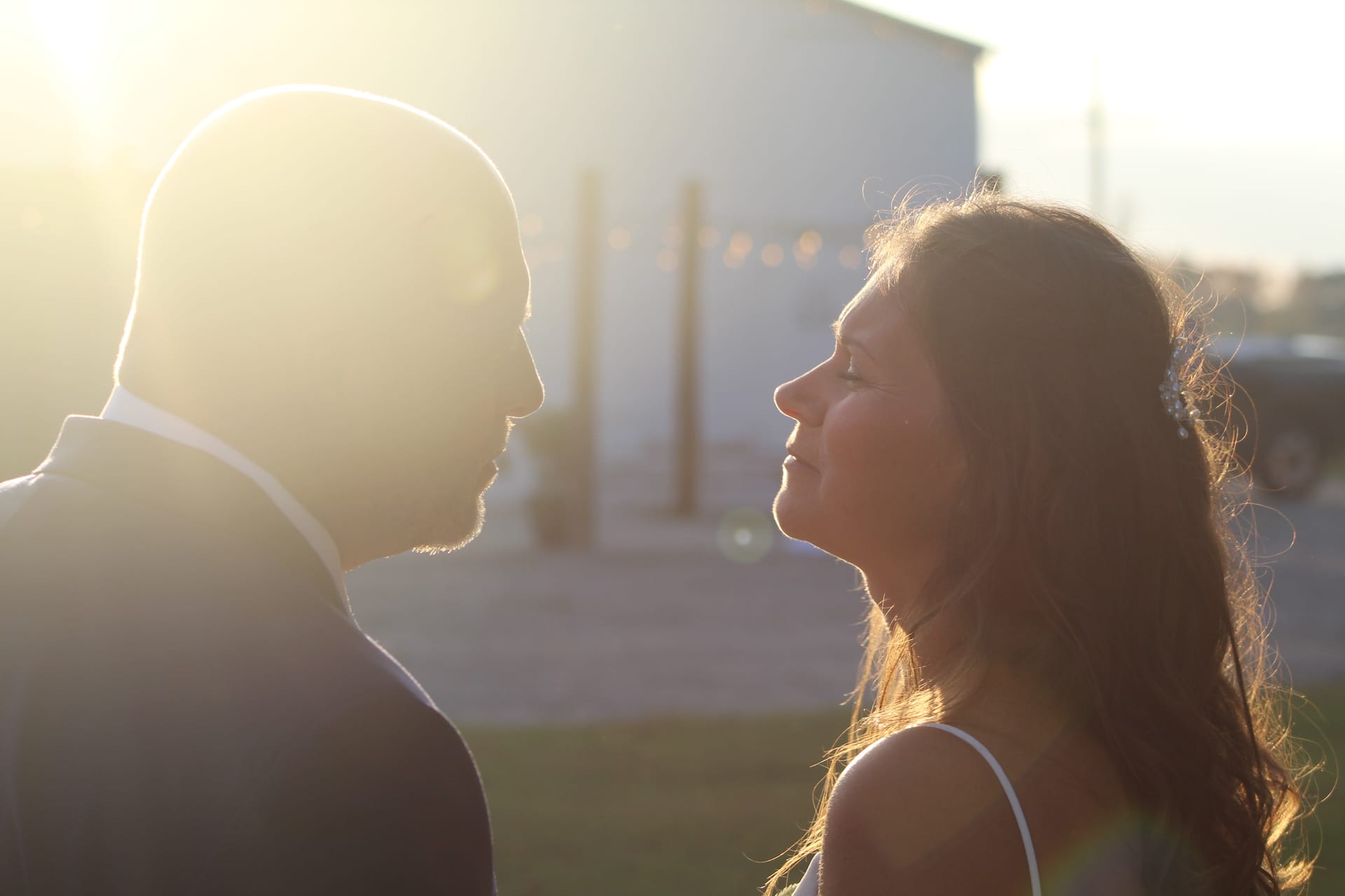 Bride and groom face each other in a glowing golden-hour backlit moment on the grounds of Scarborough House wedding venue.