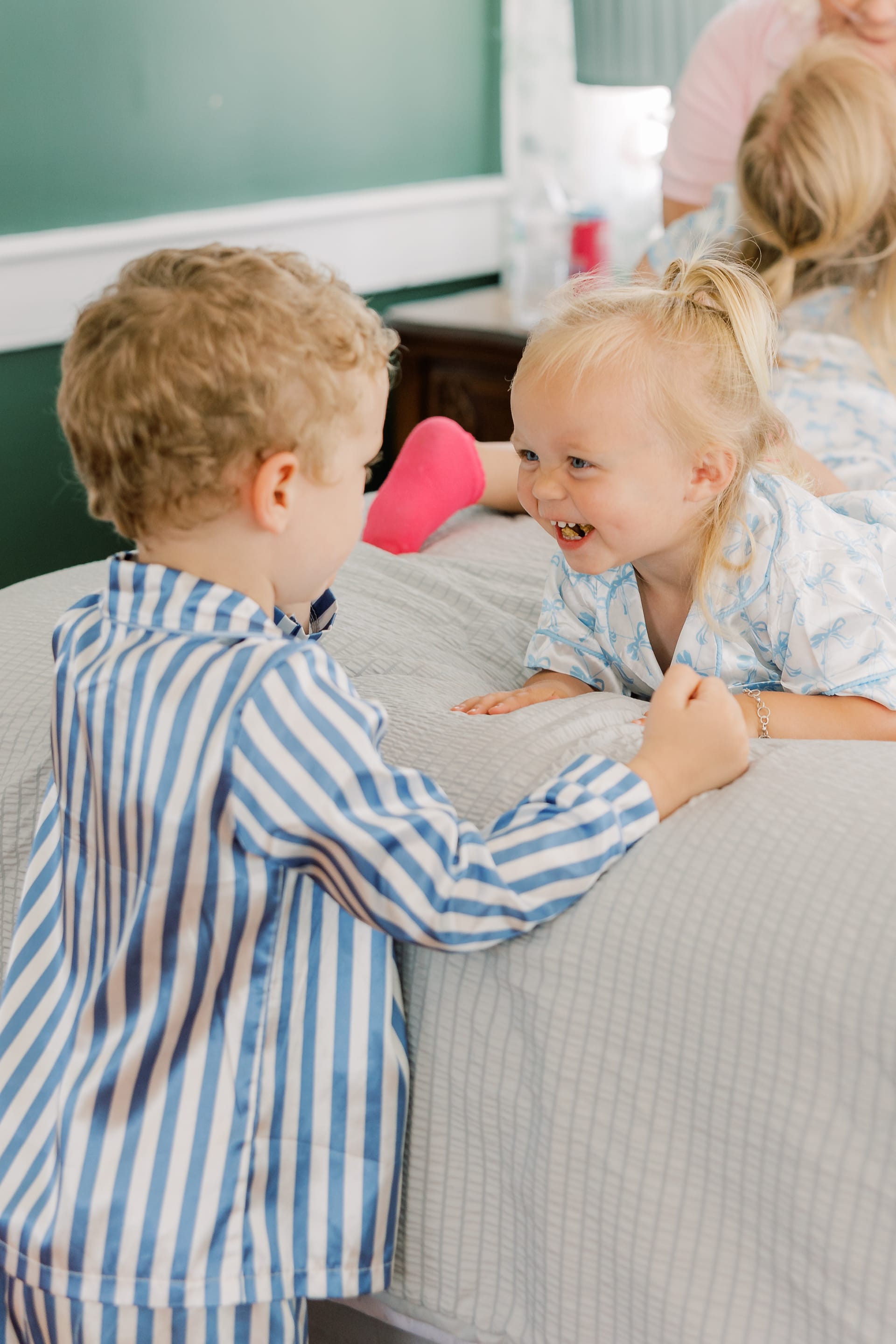 Two young children in matching pajamas laugh and play together on a bed during wedding morning preparations at Scarborough House.