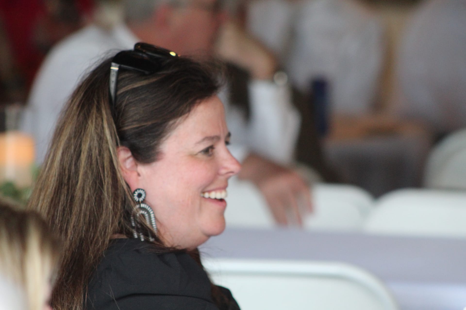 A smiling woman with dark hair and statement earrings enjoys a joyful moment during a reception at Scarborough House historic wedding venue.
