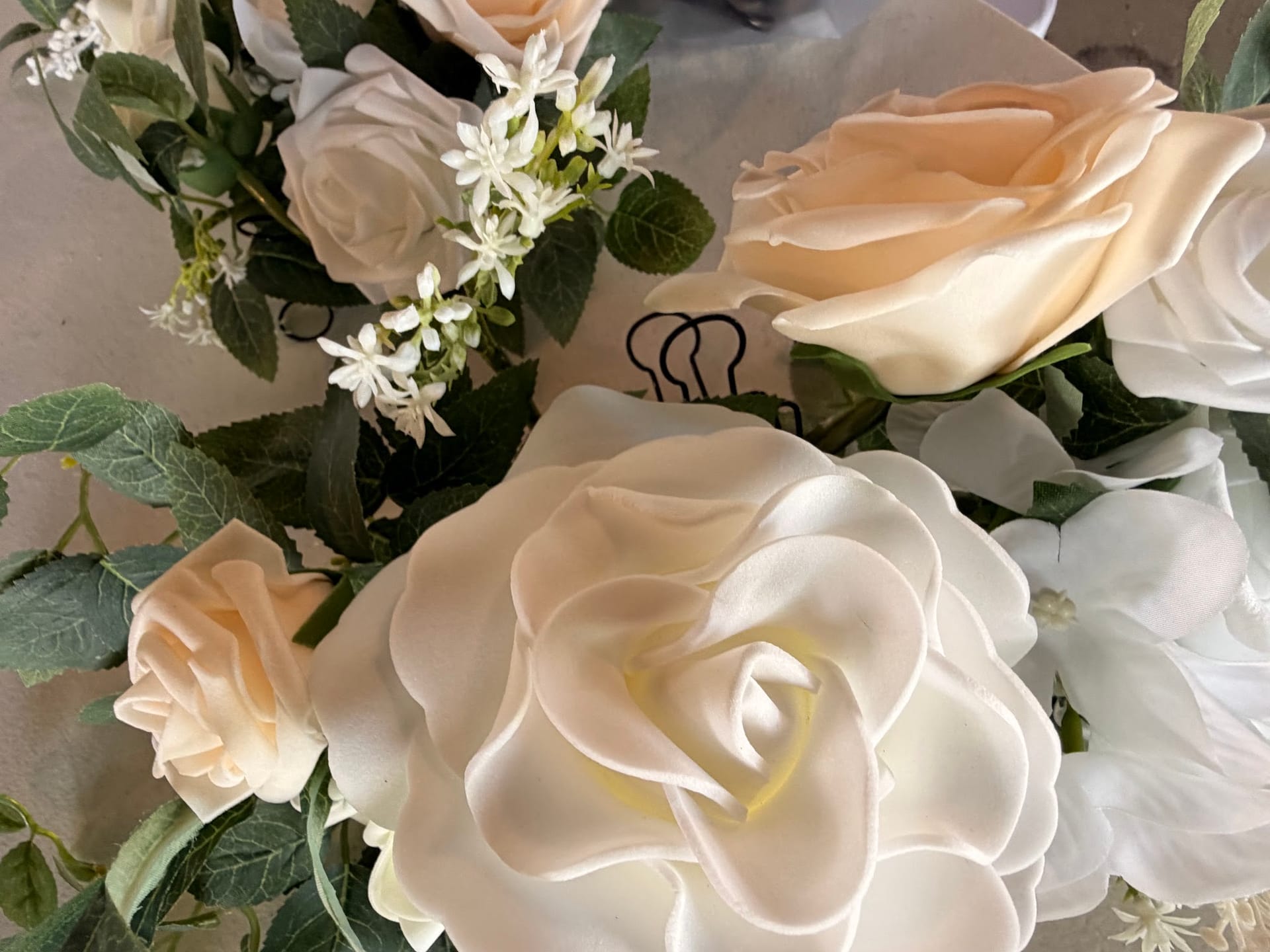 Close-up of an elegant wedding floral arrangement featuring cream and white roses with delicate white filler blooms and green foliage at Scarborough House.