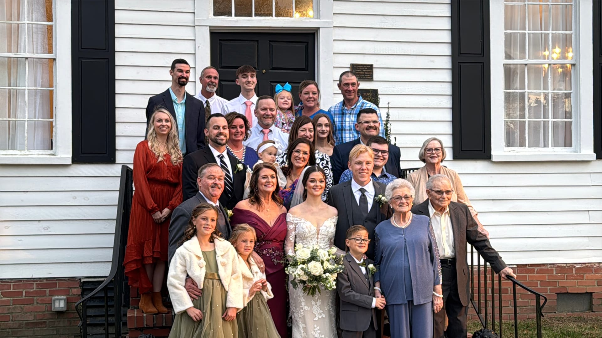 Bride and groom surrounded by a large wedding family group posed on the front steps of the historic 1821 Scarborough House manor.