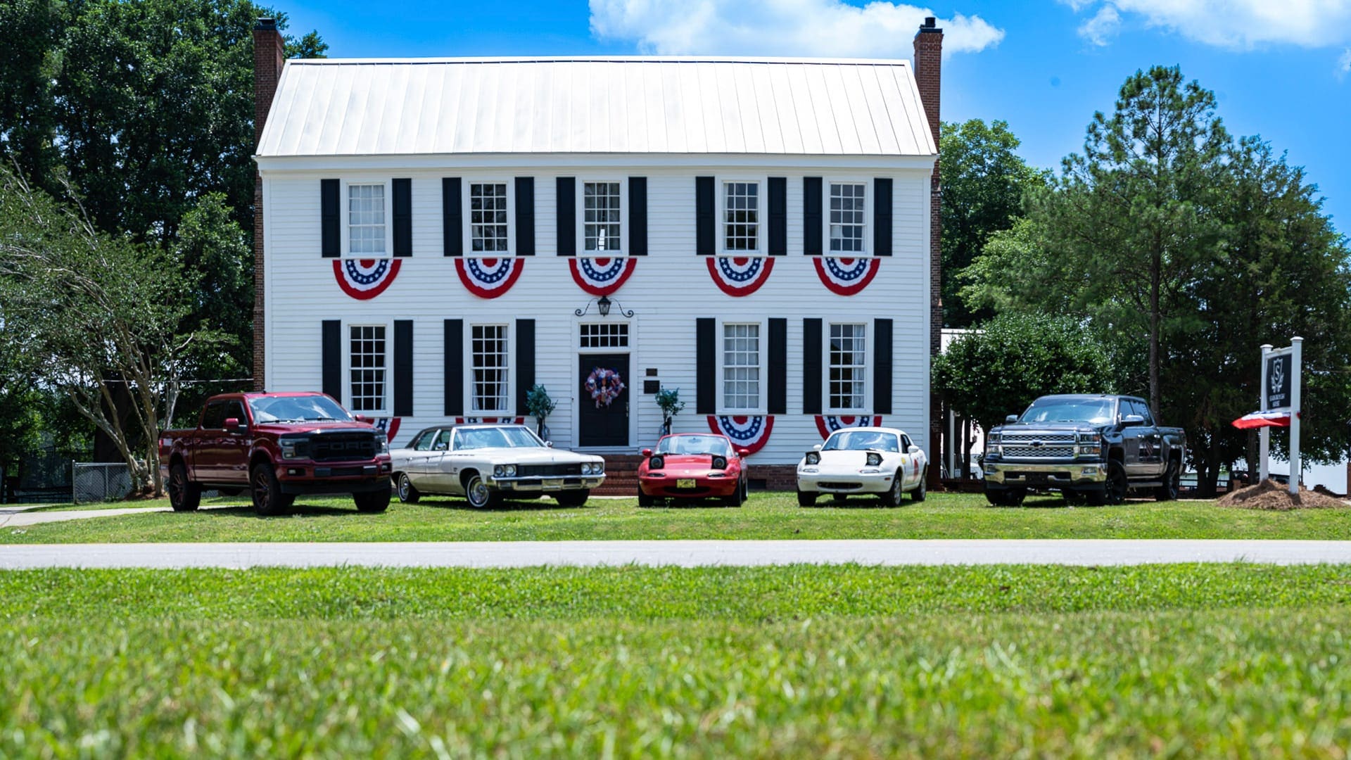 Classic and vintage cars parked in front of Scarborough House decorated with patriotic bunting
