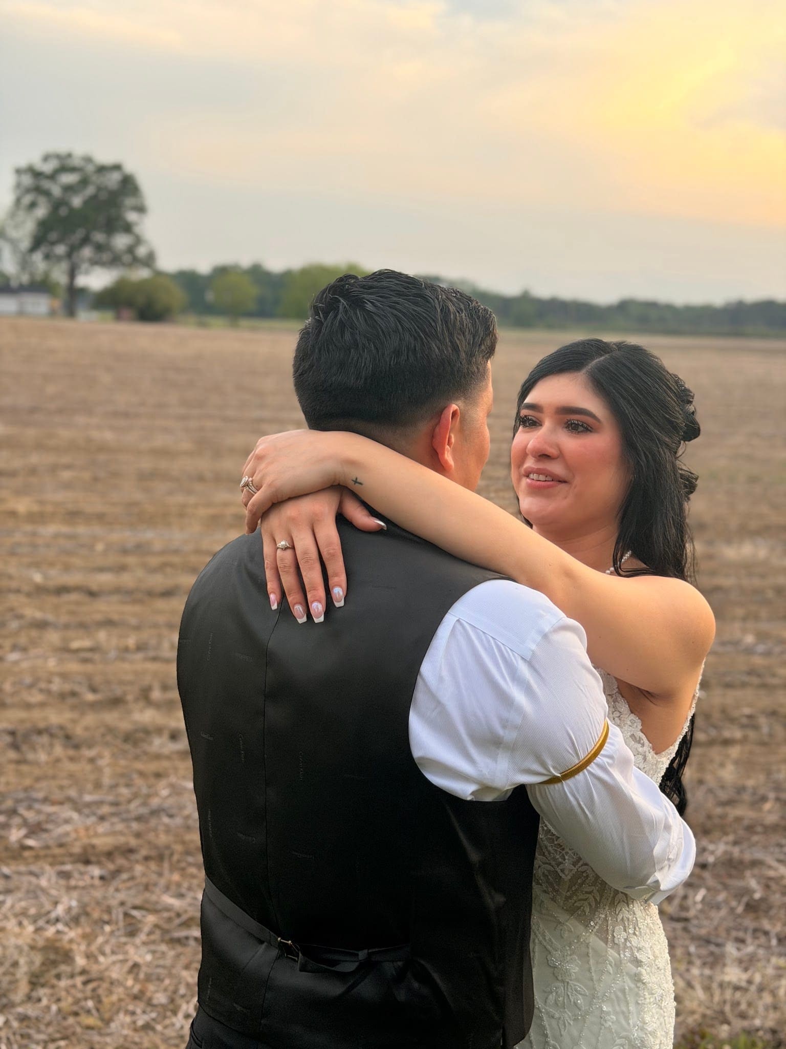 Bride with tears of joy embraces her groom as they dance in an open farmland field at golden hour at Scarborough House.