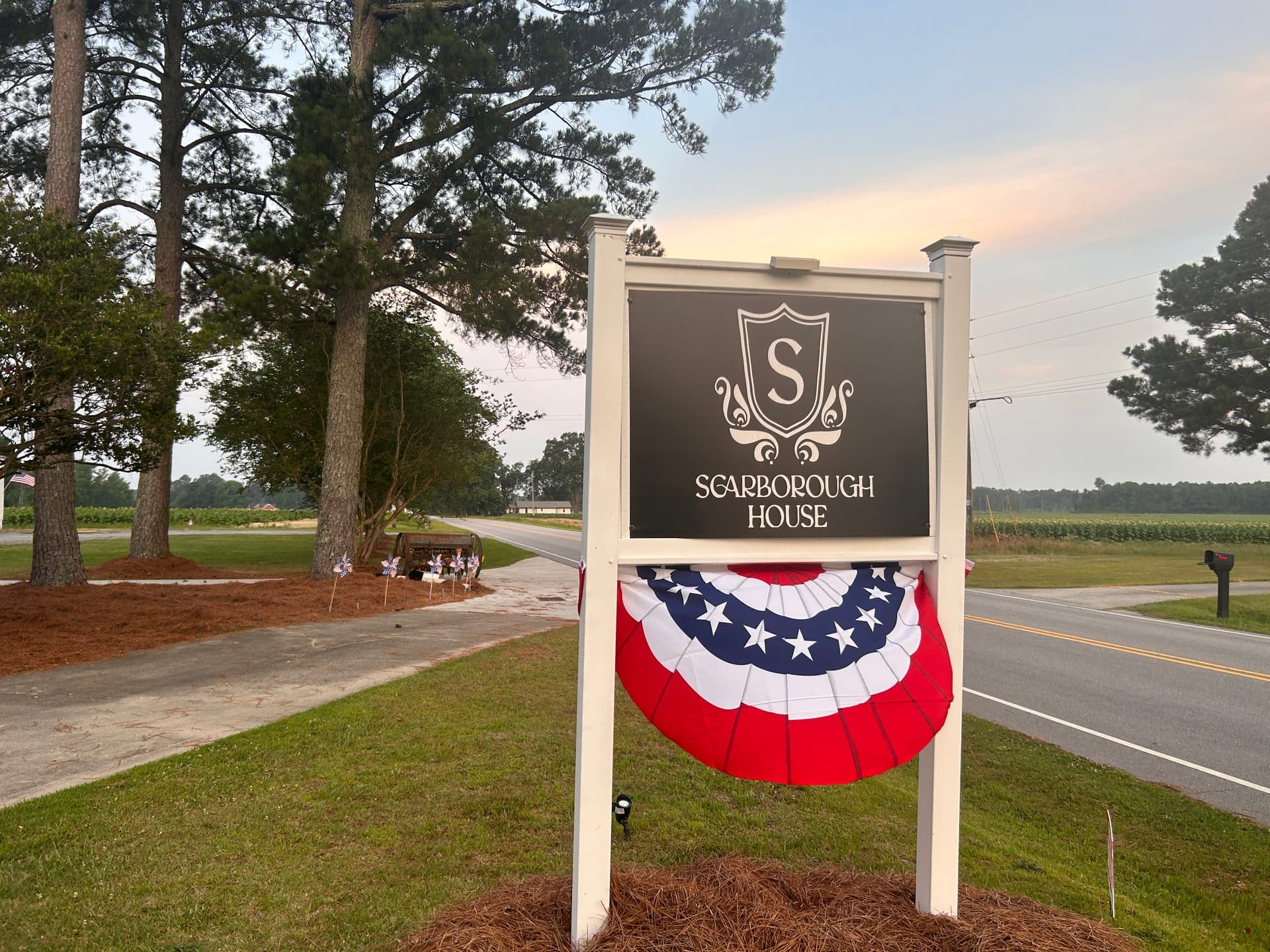 The Scarborough House estate sign with patriotic bunting beside a rural North Carolina road