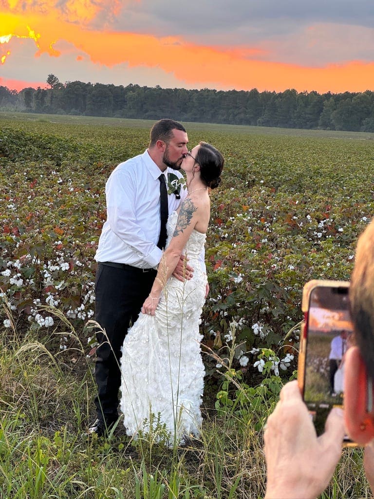 Couple walking through a cotton field at sunset near Scarborough House wedding venue in eastern NC