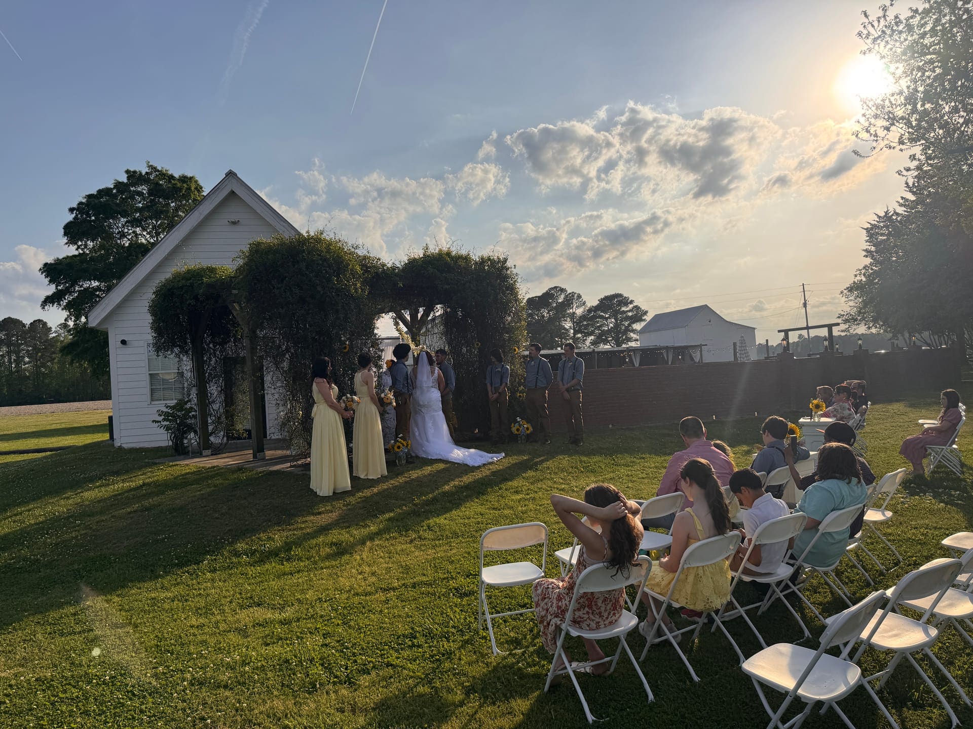 Outdoor ceremony beneath oaks with sunflowers at Scarborough House