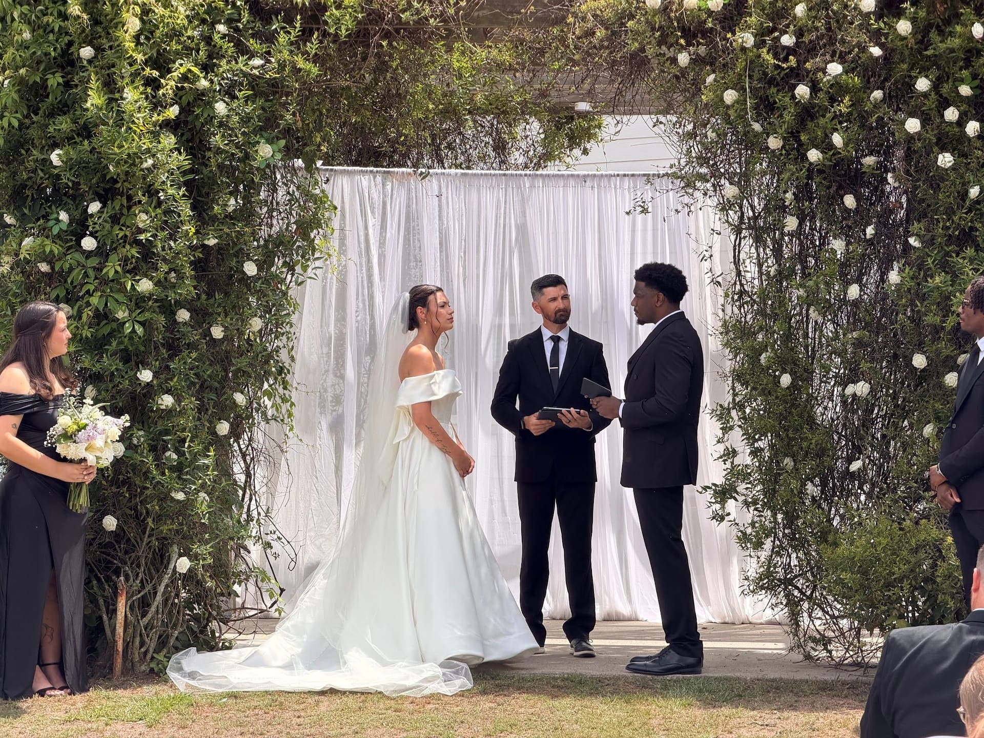 Bride and groom at the floral arch during a Scarborough House ceremony
